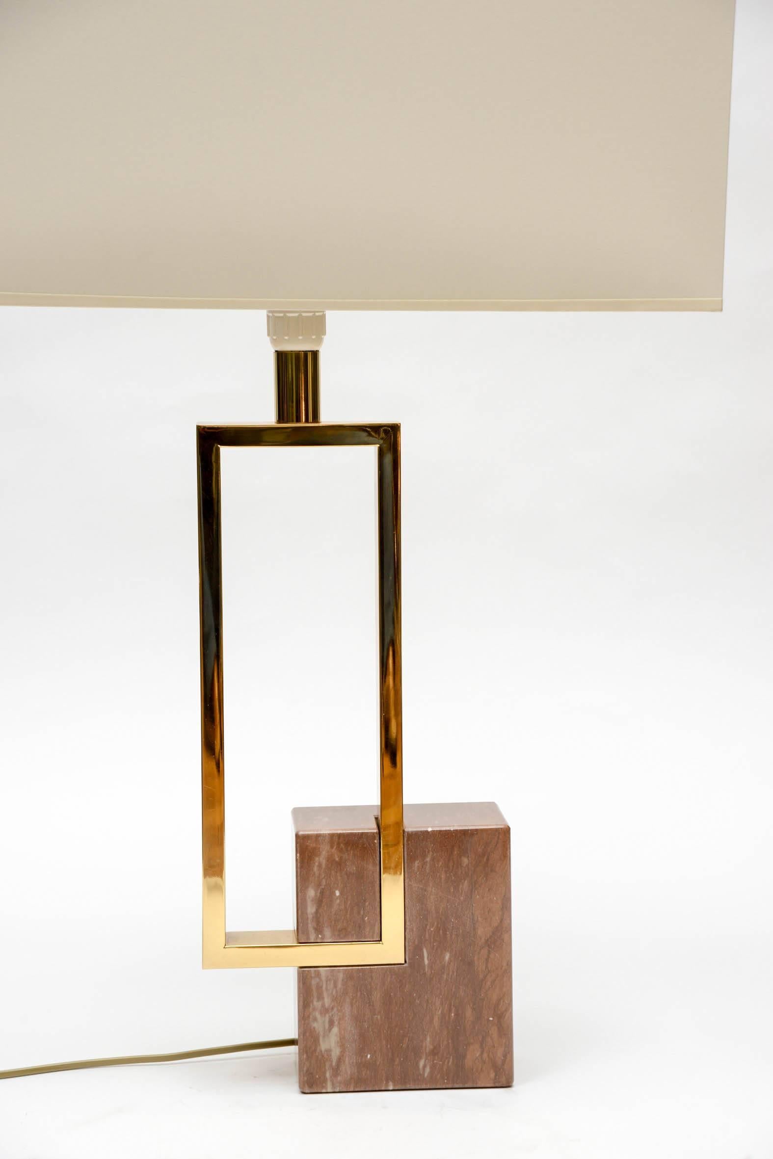 Elegant pair of lamps made of red marble feet setting a brass rectangle giving the illusion of an unbalanced structure.