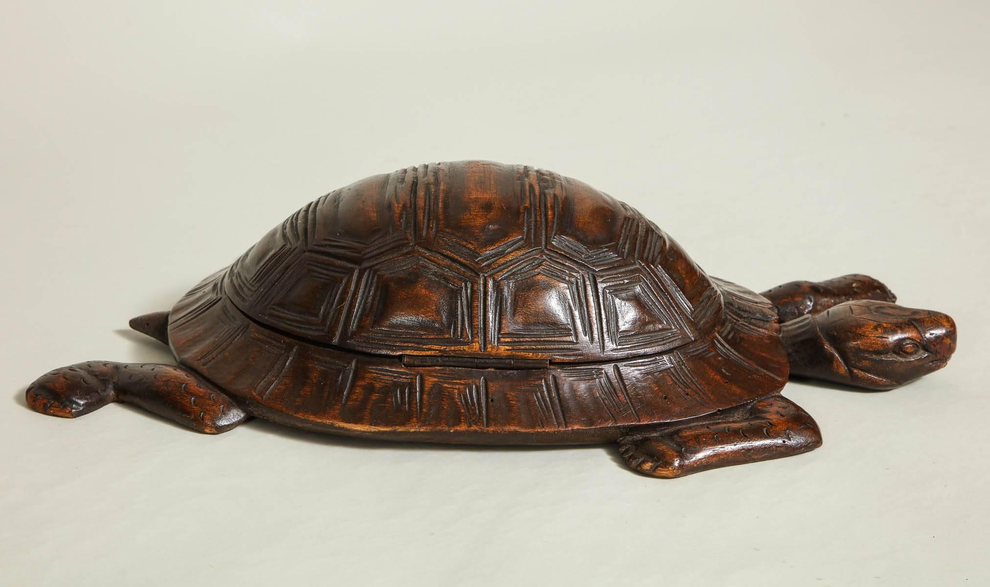 A charming box in the shape of a box turtle, carved of wood with legs, head and tail and hinged shell that lifts to reveal a lined interior for storing jewelry. Good color and patina, English, 19th century.
