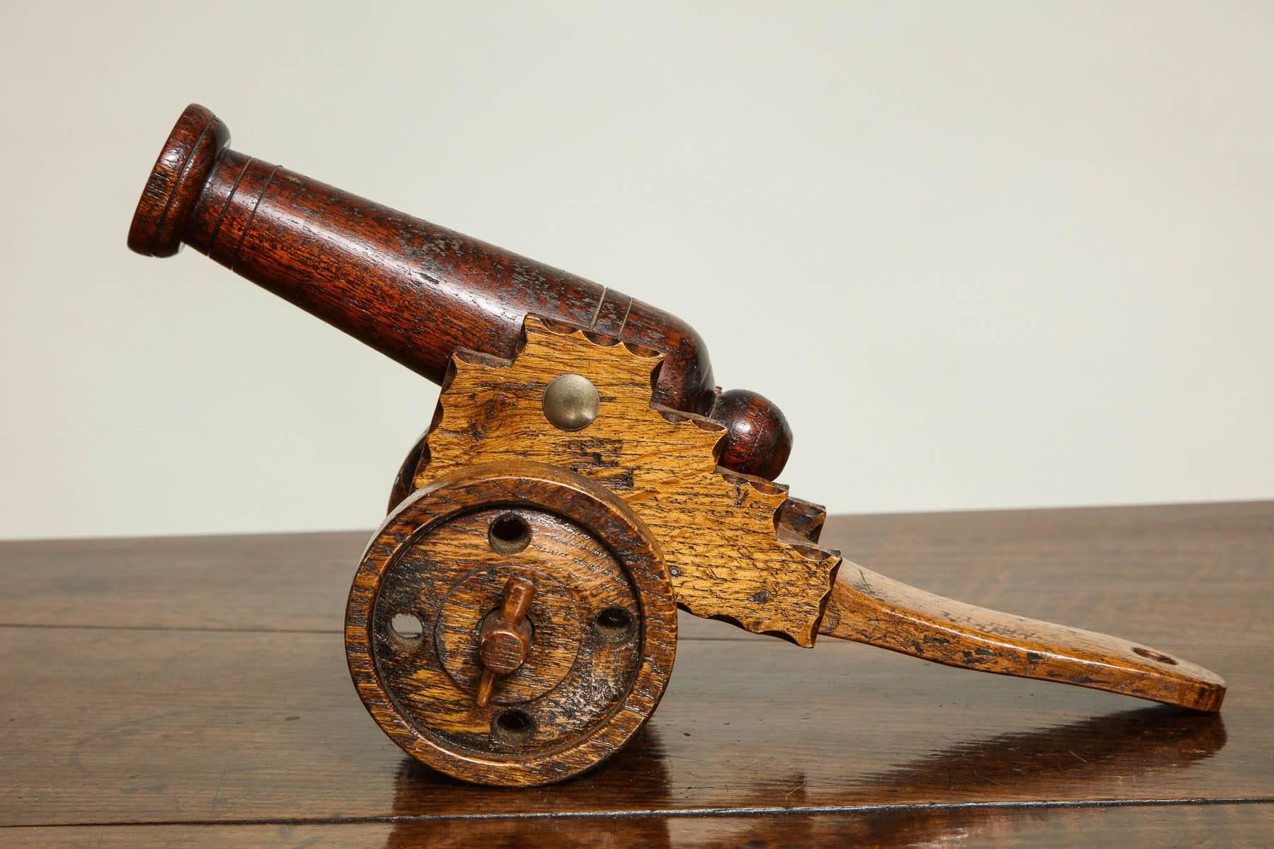Unusual early 20th century hand modeled cannon, the turned mahogany barrel with flared mouth, the oak carriage with turned wheels held by wedges and on shaped frame, the whole with pleasing color and good proportions.