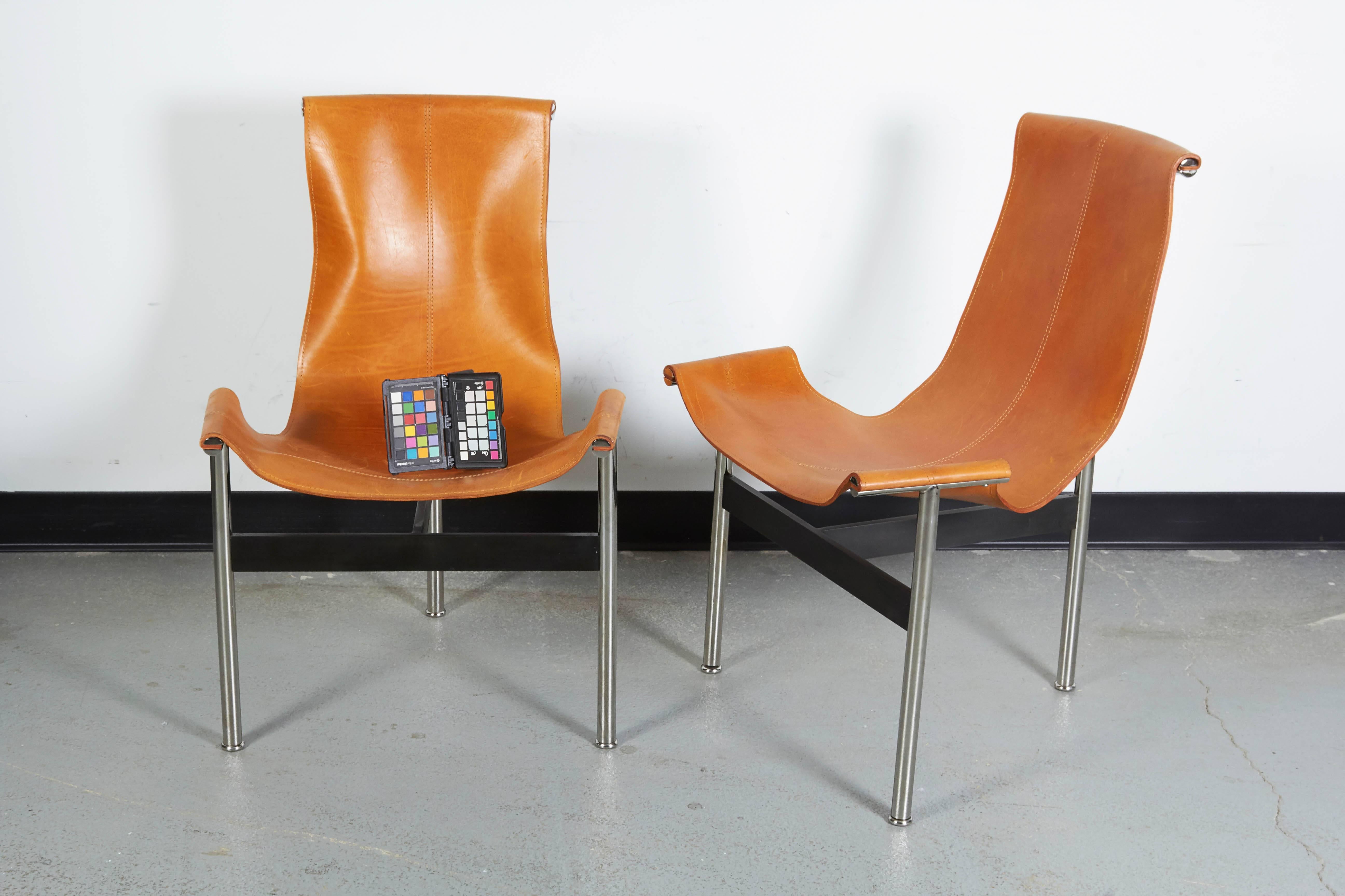 Elegant three-legged chairs with chrome-plated tubular steel legs joined by enameled steel stretchers with leather sling seat. Note one chair shows wear to leather on top rail; otherwise in excellent condition. 

Designed by William Katavolos for