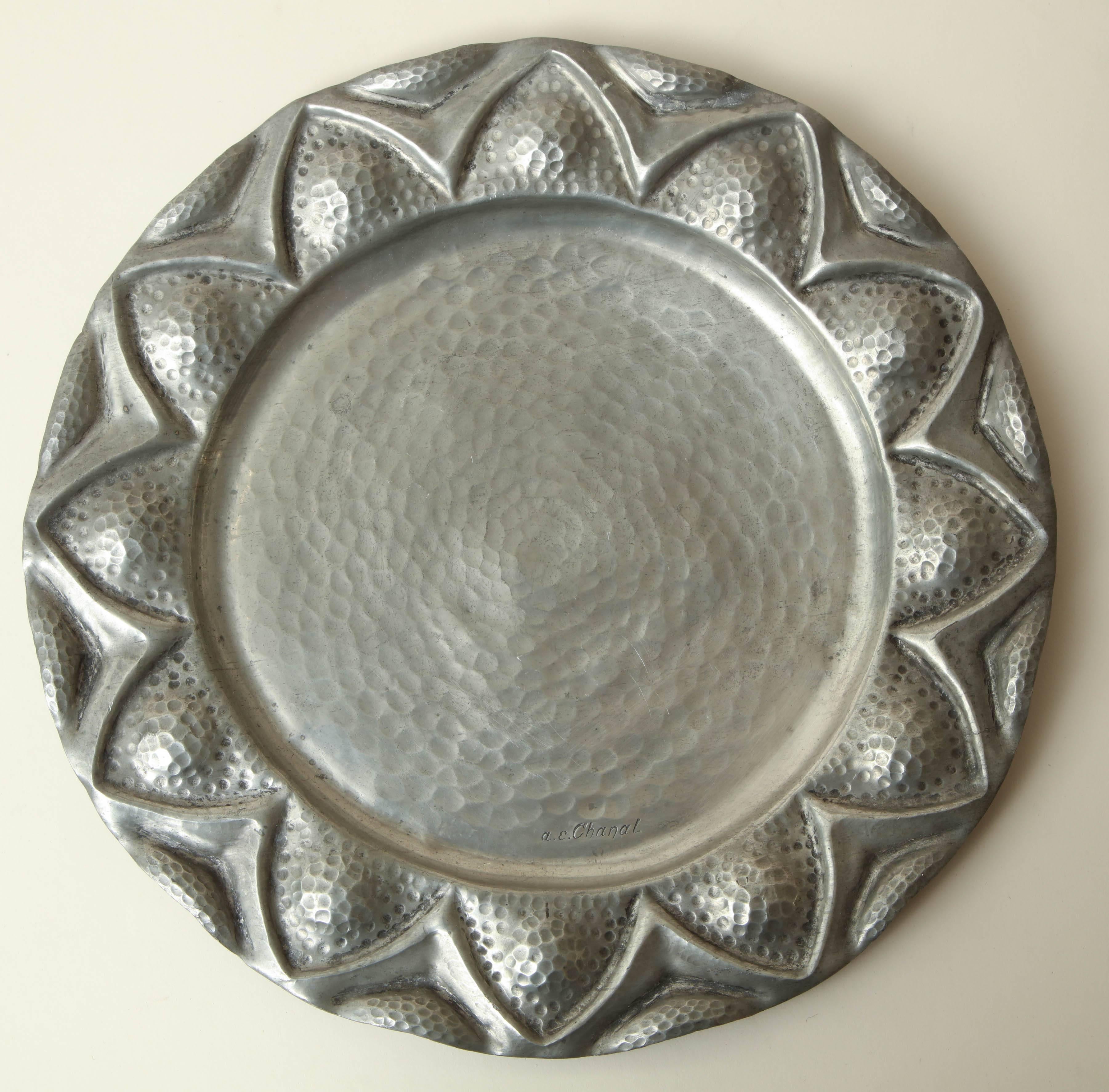 Hand-wrought dinanderie pewter plate with border of triangles around circumference.
Inscribed a.e. Chanal on top.
  