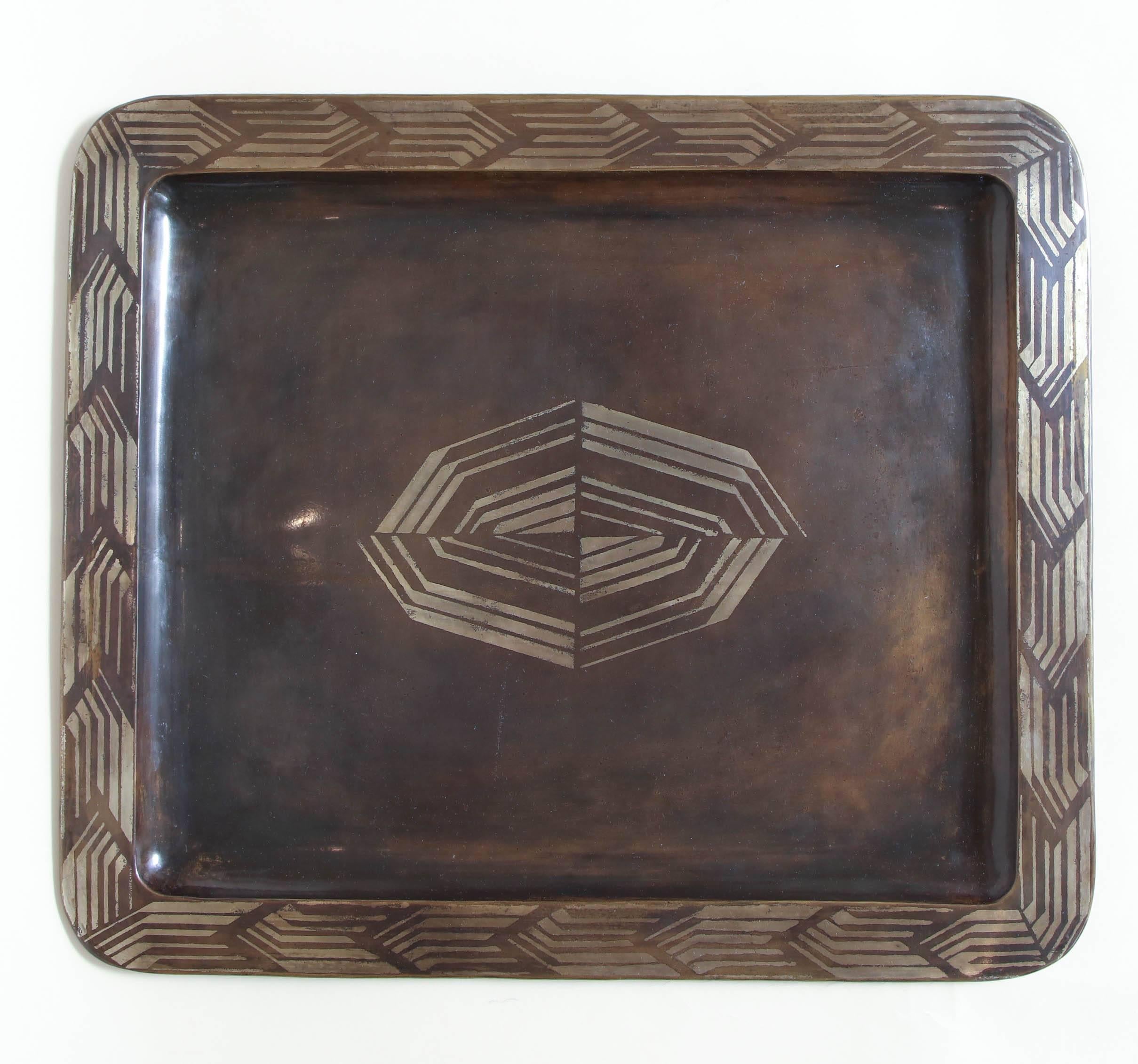 Dinanderie brass tray inlaid with silver around the edge and centrally in a geometric design.
Inscribed F Grange underneath.
 