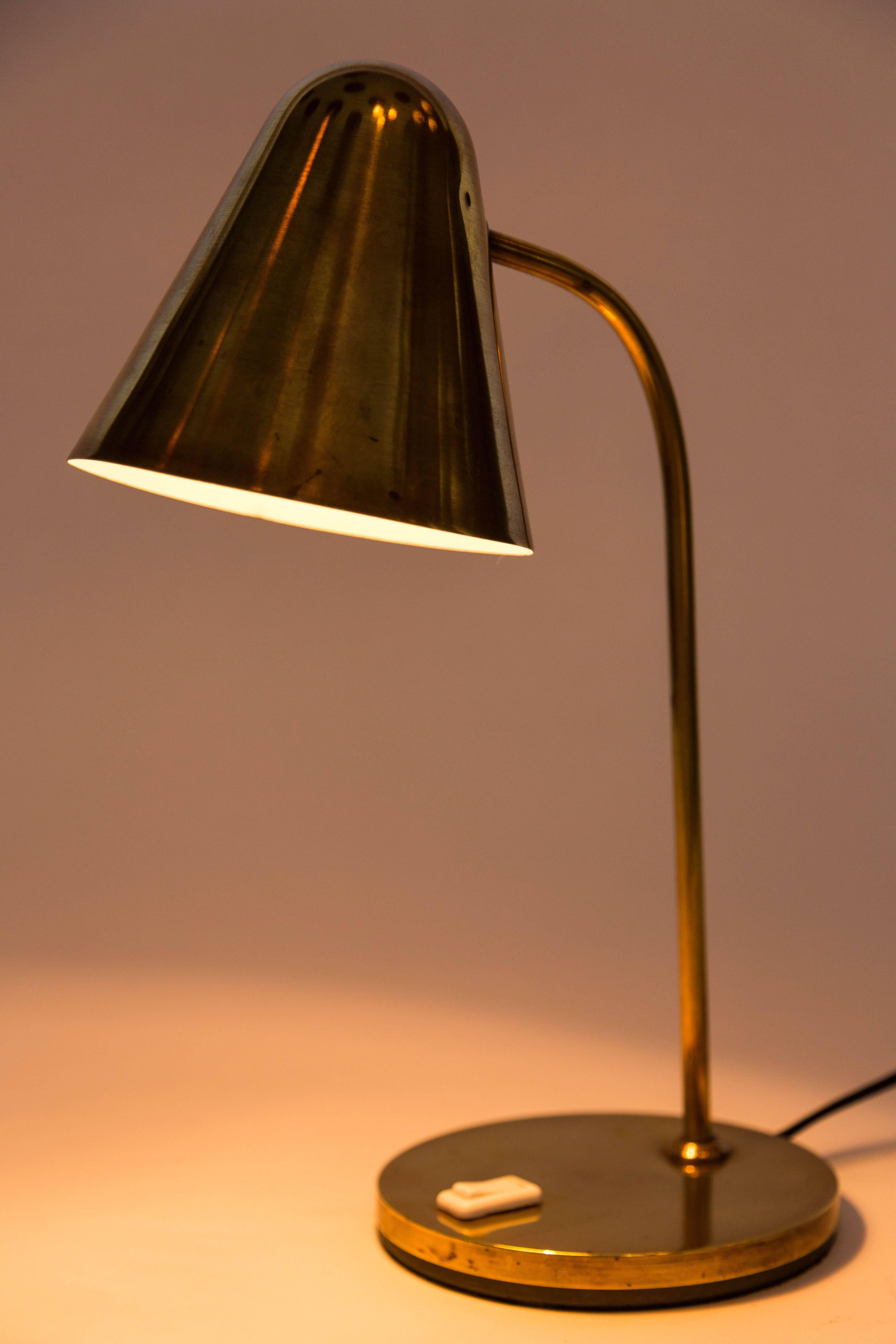 1950s brass table lamp attributed to Jacques Biny. An exceptionally clean and simple design executed in patinated brass with white painted inner shade. Quintessentially midcentury French in its conception and execution attributed to the incomparable