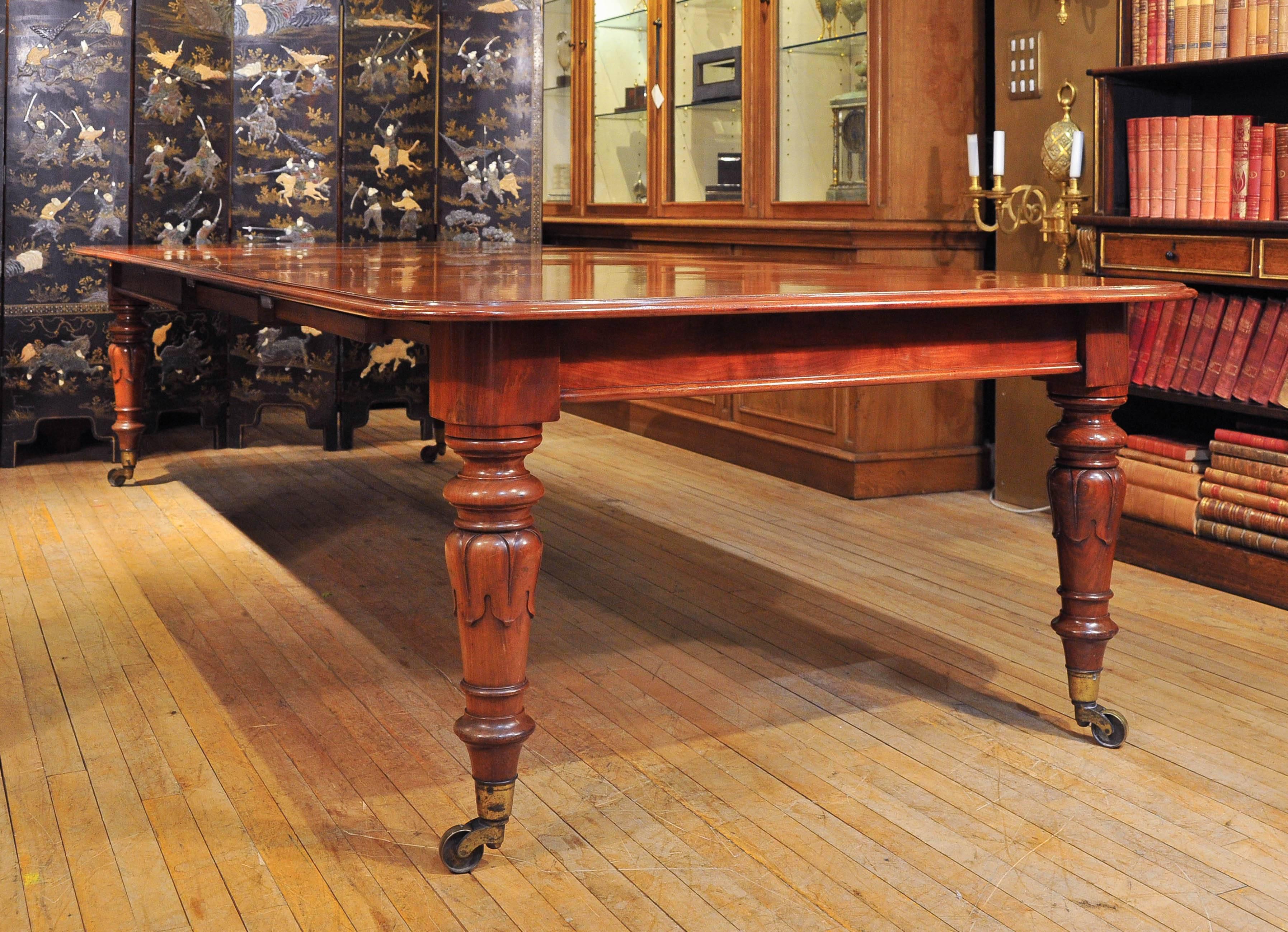 This ample and very imposing mahogany dining table features lovely tulip shaped leg supports ending on oversized brass castors. The table has three leaves and is stamped Johnstone and Jeanes, very well-known and highly regarded cabinet makers of the