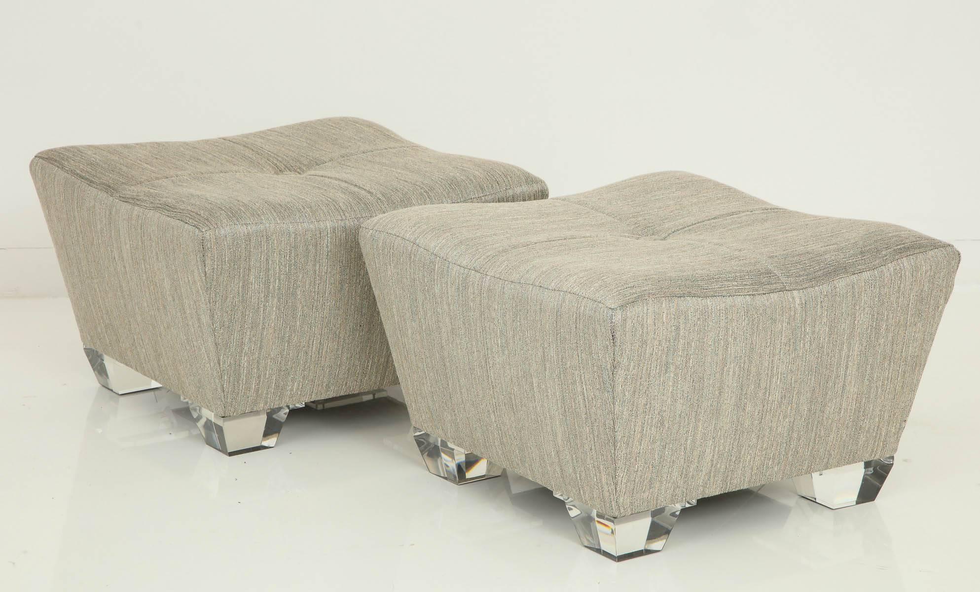 Pair of glamorous ottomans that have a Trapezoid shape.
The ottomans have been newly reupholstered in a luxurious fabric and are set up on thick Lucite legs that follow the same trapezoid shape as the ottomans.