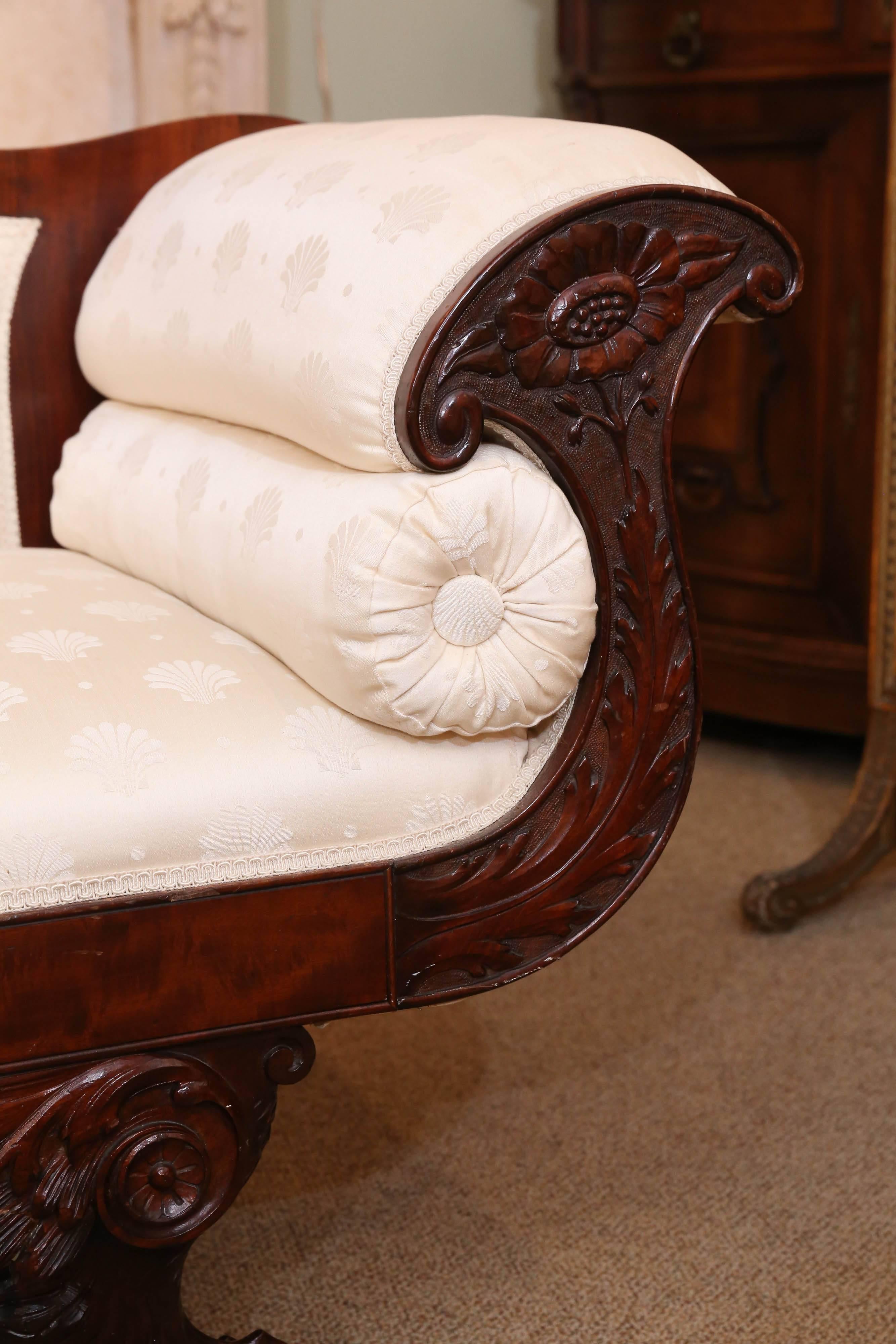 Classic American Empire sofa made of flame mahogany with rolled arms
that are carved with a floral motif. It features a rolled crest with a curled
carved end. It has a tufted bolster on each side and features a claw
foot carved on the front and