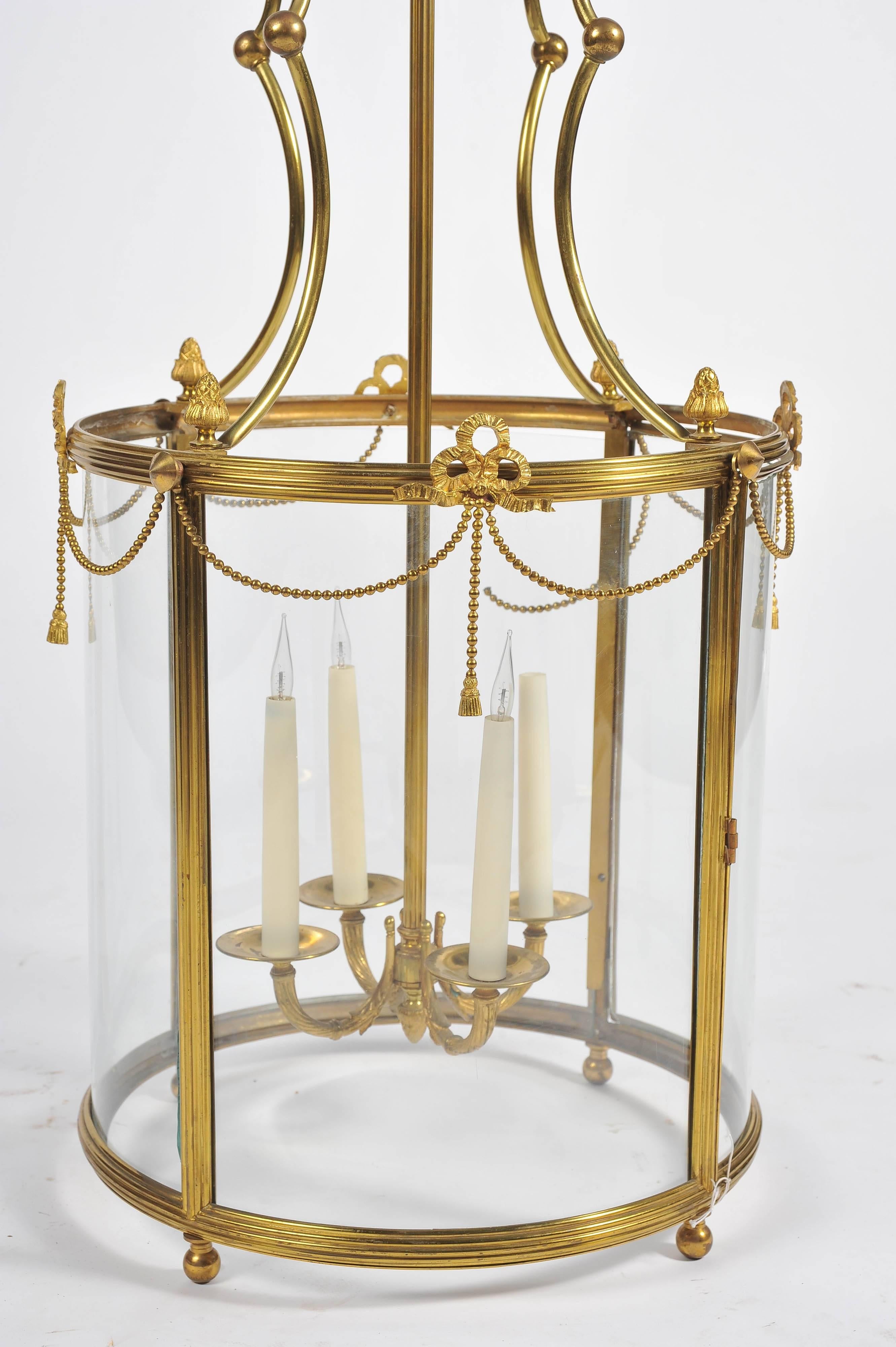 A good quality Regency style brass hall lantern, having bowed glass panels swag and ribbon decoration and a four branch sconce within.