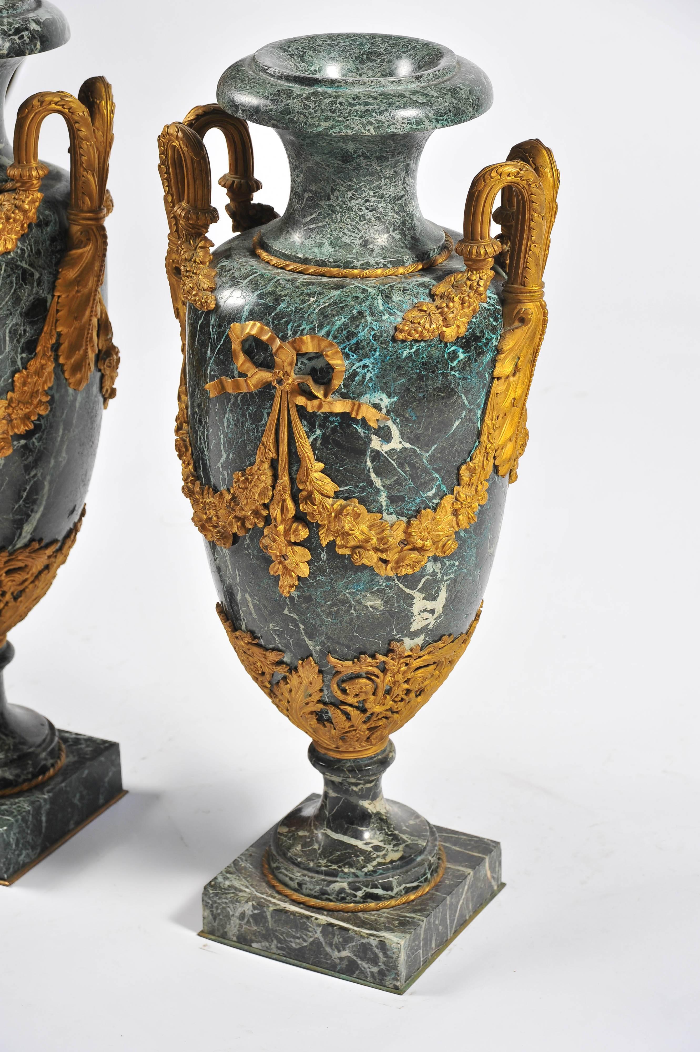 A good quality large pair of Louis XV style green marble urns, having gilded ormolu scrolling handles with foliate and ribbon swags.