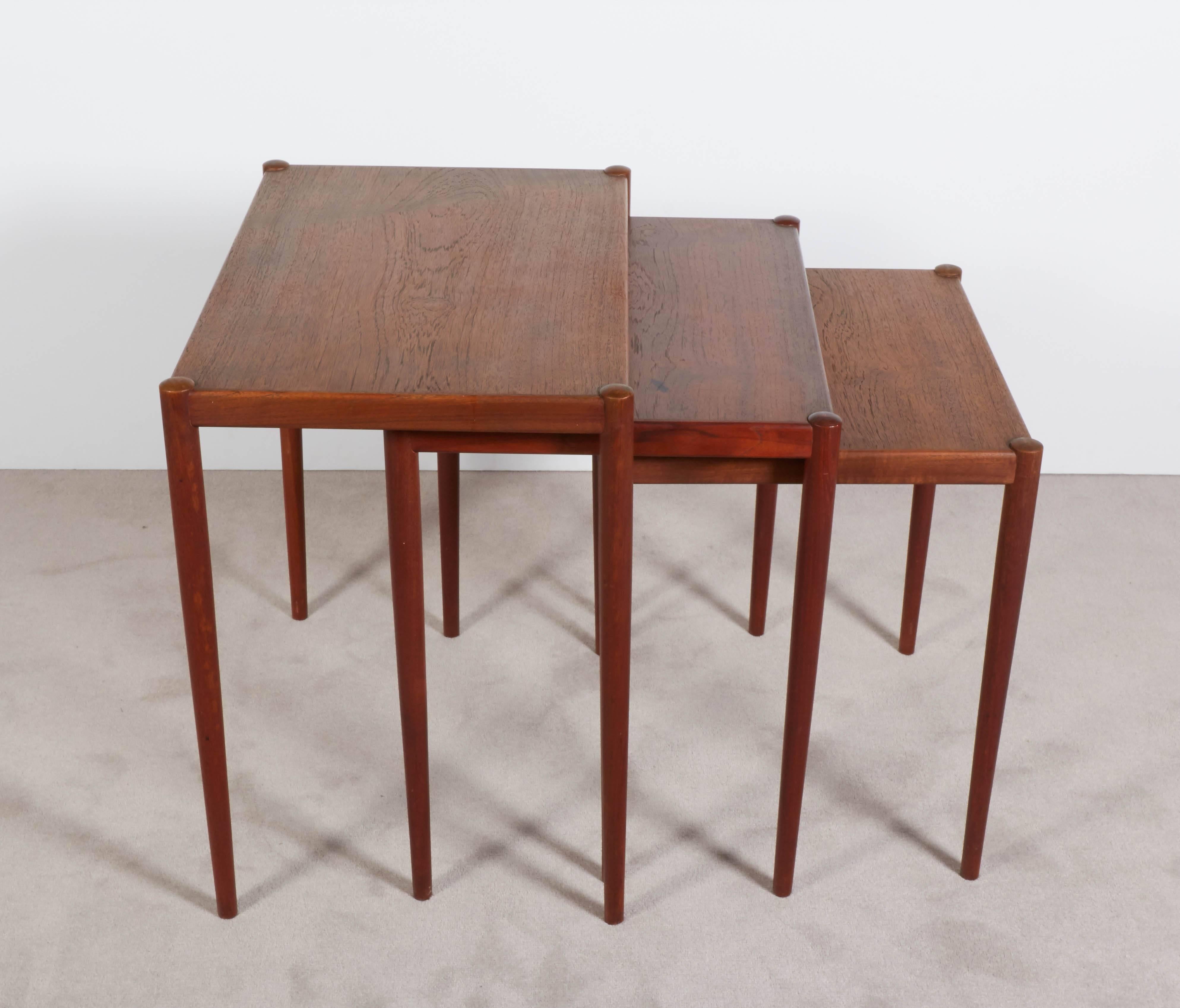 Danish, circa 1960s nesting tables by Poul Jensen, designed in the Scandinavian Modern style, entirely in teak on tapered legs. Markings include manufacturer's label, signed [P. Jensen] to the underside of the tabletop. Very good condition, minimal