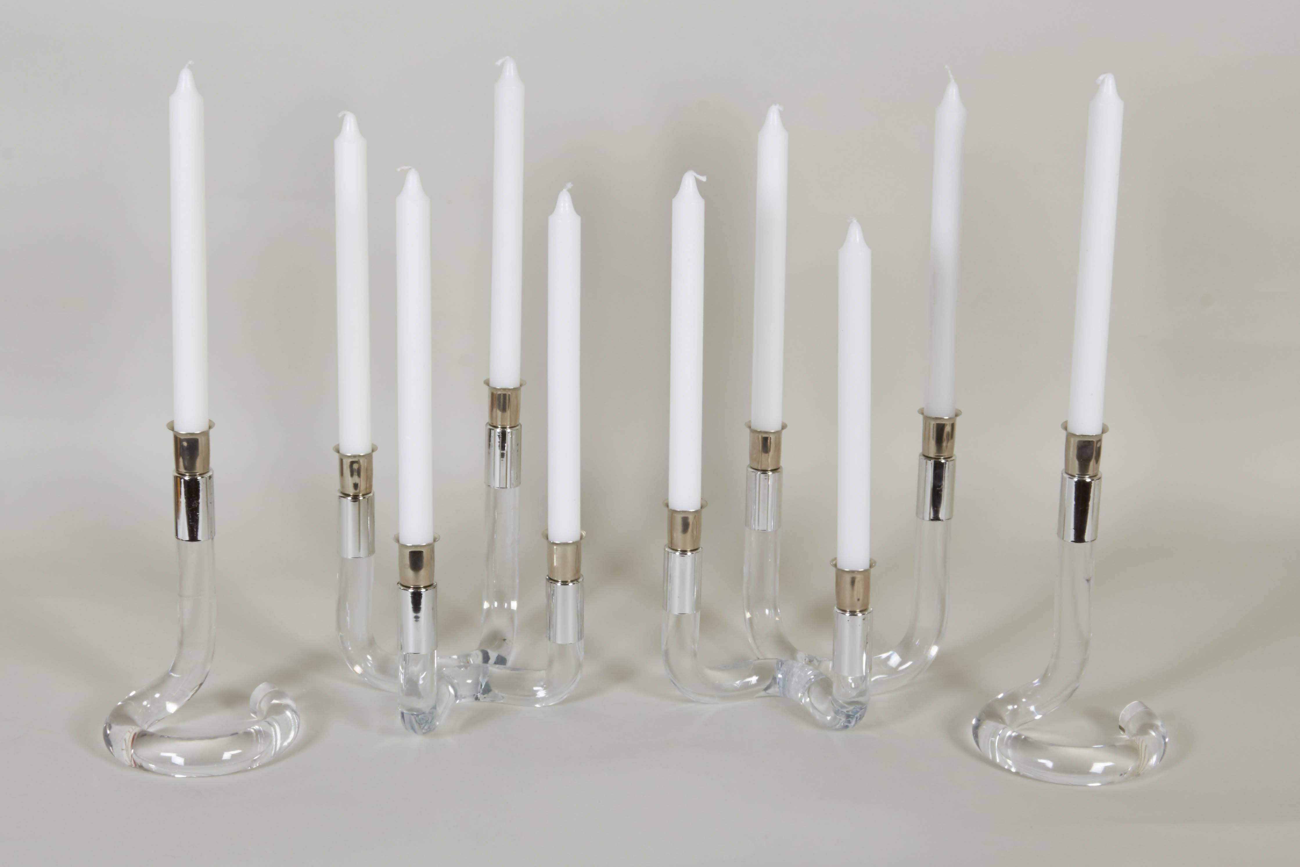A set of four Mid-Century Modern candleholders, two single-light and two four-light, produced circa 1960s-1970s, styled in the manner of Dorothy Thorpe, each with chrome bobeches on curvaceous clear Lucite stems. Excellent vintage condition,