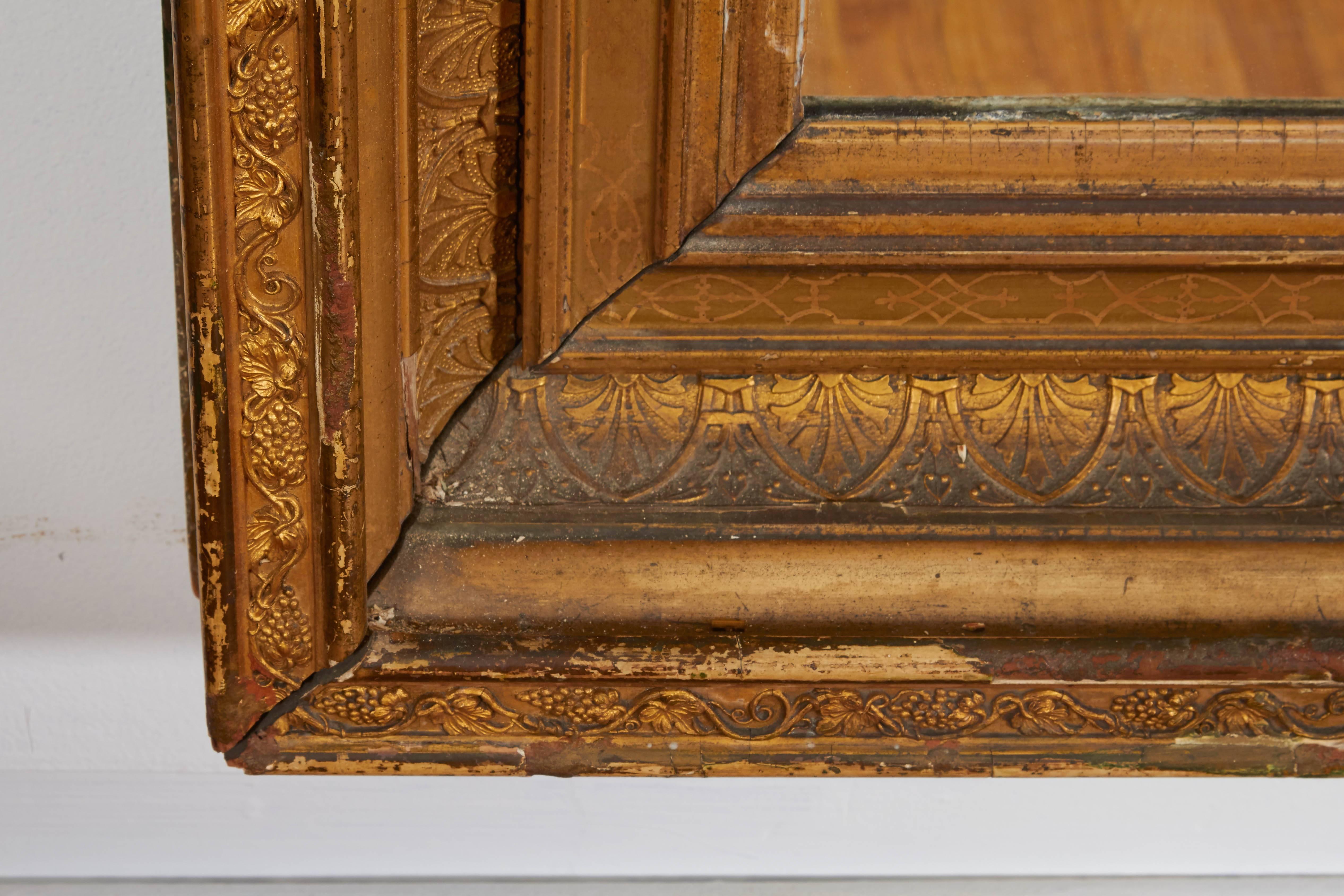 Un grand miroir de cheminée ou de pilier du début du 20e siècle, cadre de style Empire en bois doré détaillé avec des motifs classiques, y compris des hymnes et des vignes de raisin traînantes. Excellent état ancien, usure du cadre et du verre