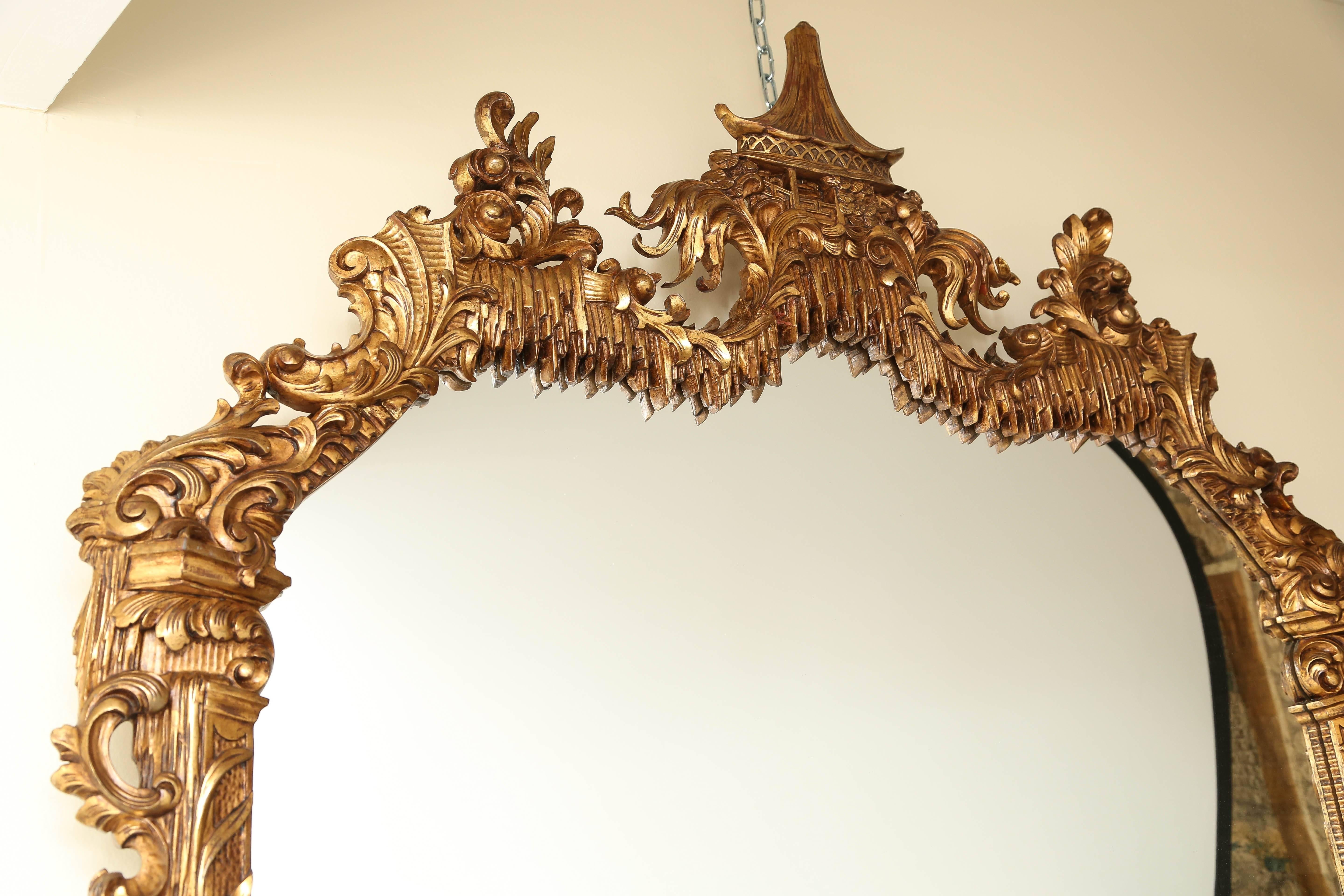Magnificent giltwood mirror. In the Chinese Chippendale Style. Adorned with acanthus leaves, elegant scrolled carvings. Crowned with a Pagoda style pavillion surmounted in a 'floating' garden setting with a lambrequin apron. Bottom Apron featuring a