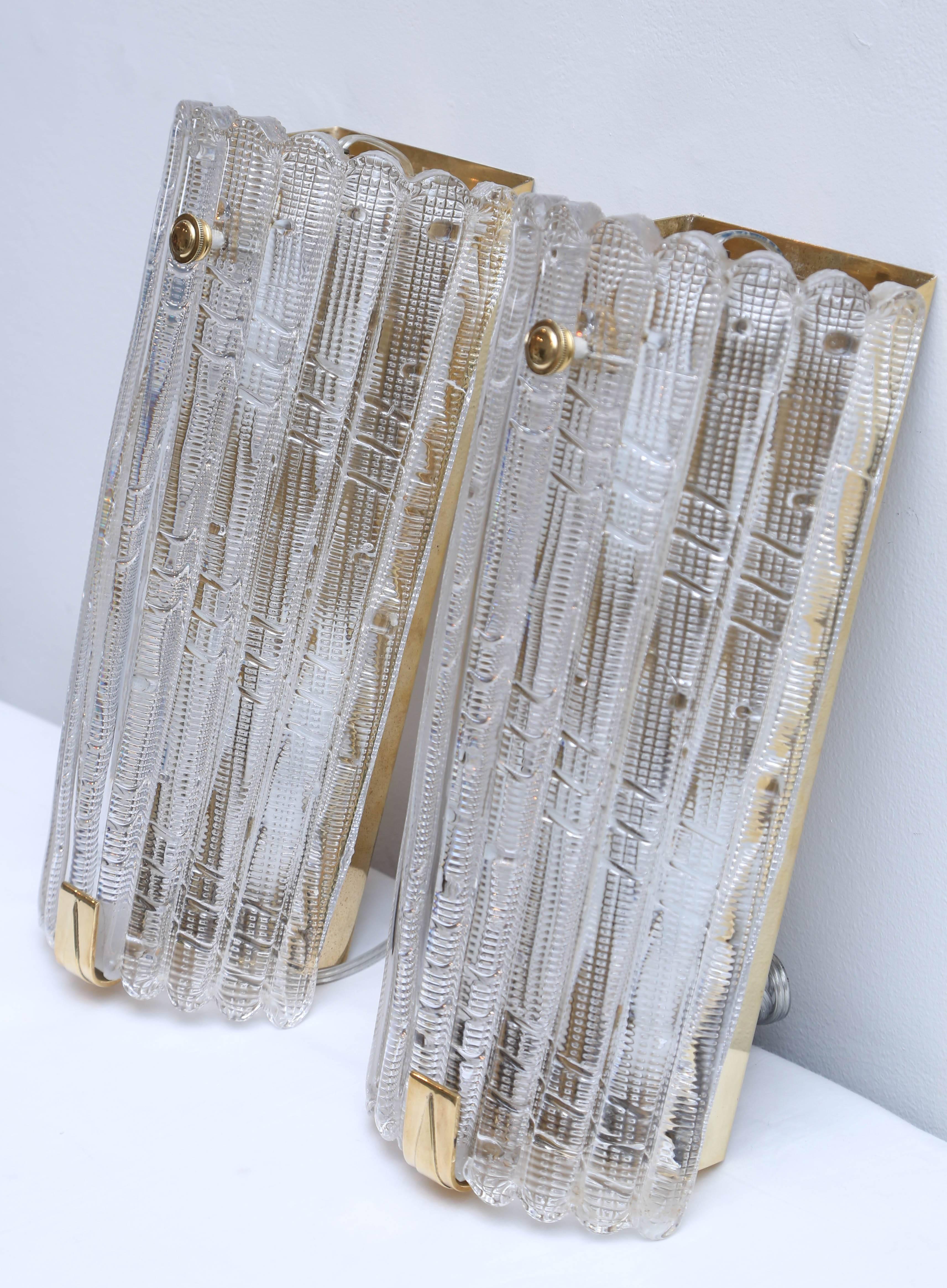 Pair of unique large Orrefors crystal wall sconces by Carl Fagerlund, Sweden,
circa 1960s, Classic carved textured and diagonal pattern on large crystal 
fluted clear crystal covers, Brass backplates and lovely substantial brass
brackets and round