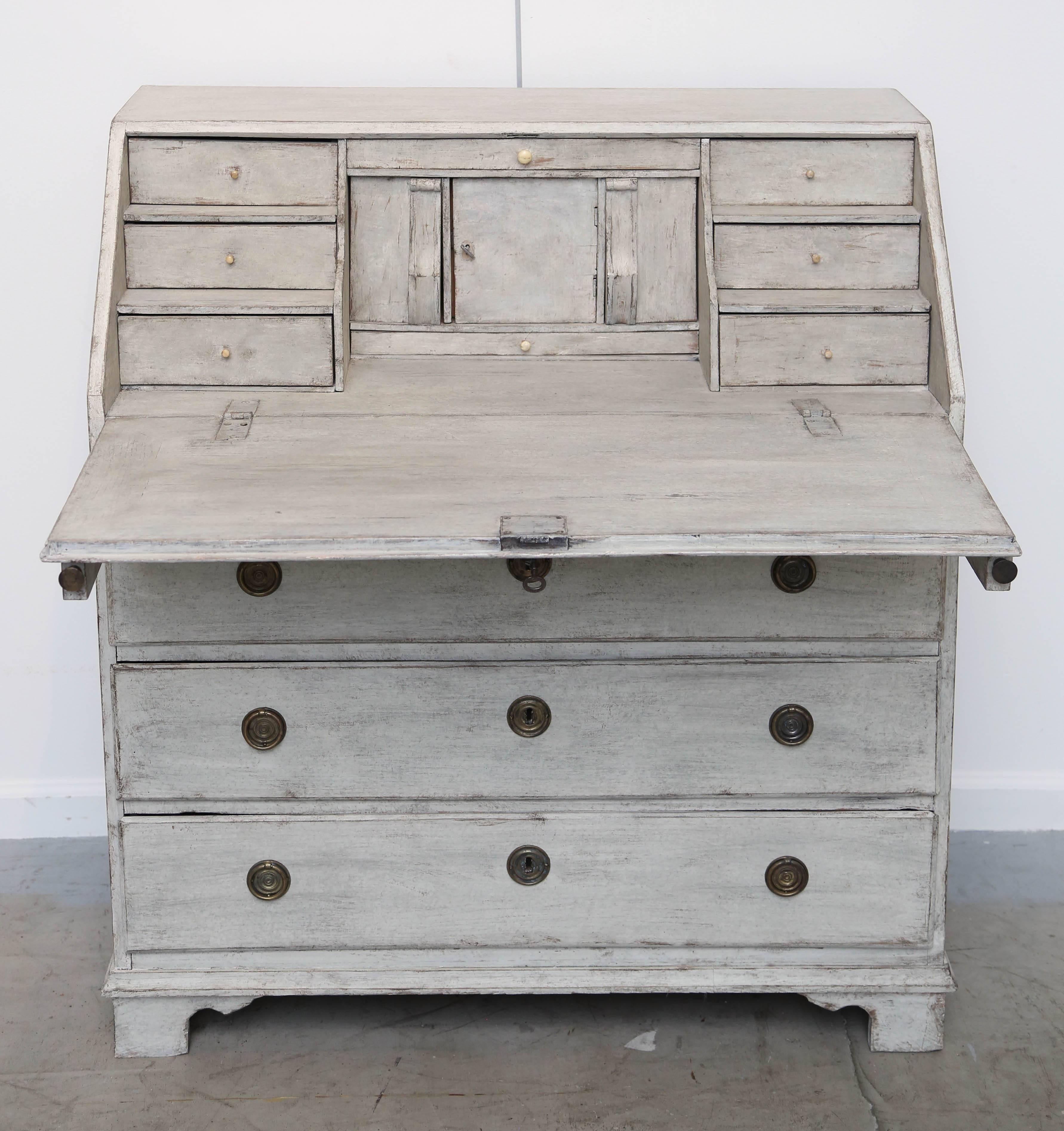 Terrific antique Swedish period painted slant front desk refreshed distressed greyish- white with bone pulls on the upper compartments. There is a lockable centre space flanked by drawers. This charming desk has three dove tail drawers and metal