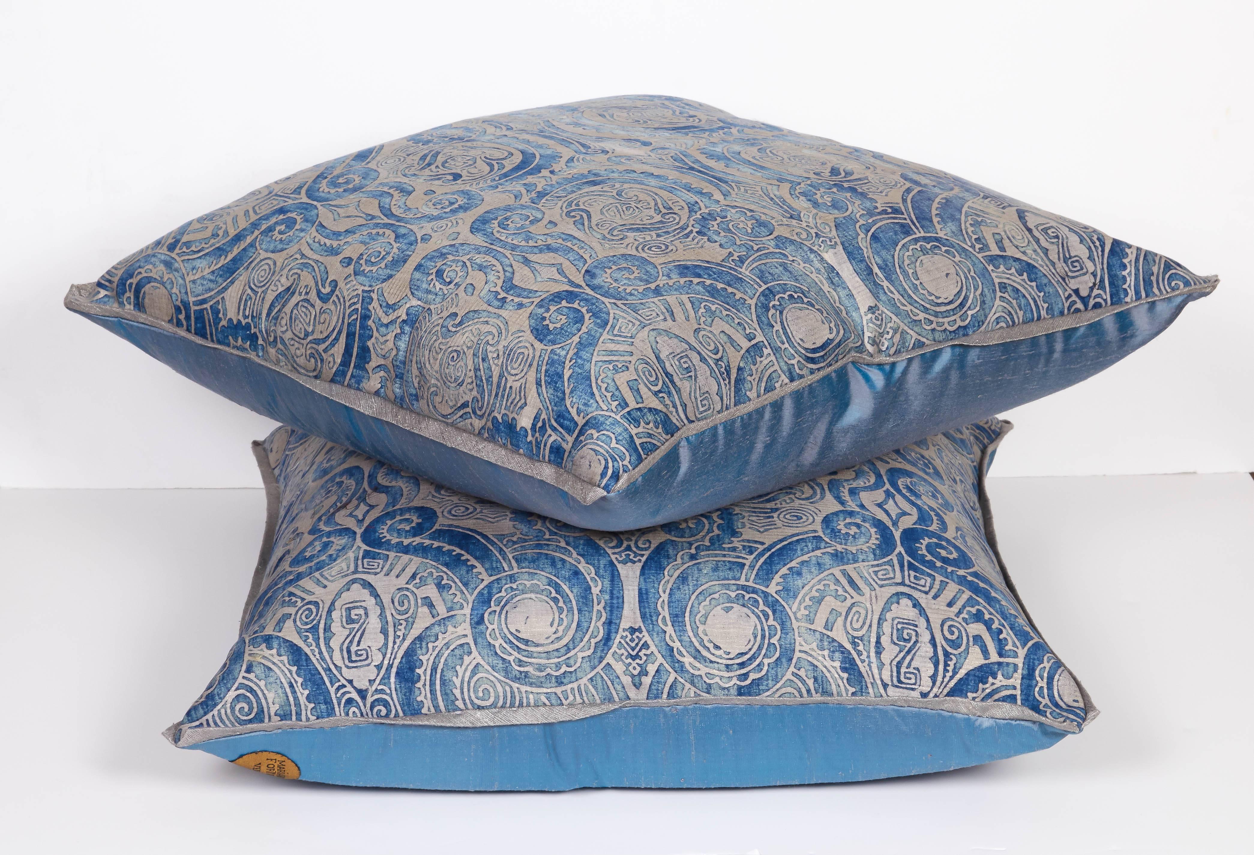 A pair of Fortuny fabric cushions in the Peruviano pattern, indigo and silver color way with silk bias edging and blue taffeta backing material, the pattern, a Peruvian inspired design with scroll motif. Newly made using vintage Fortuny fabric,