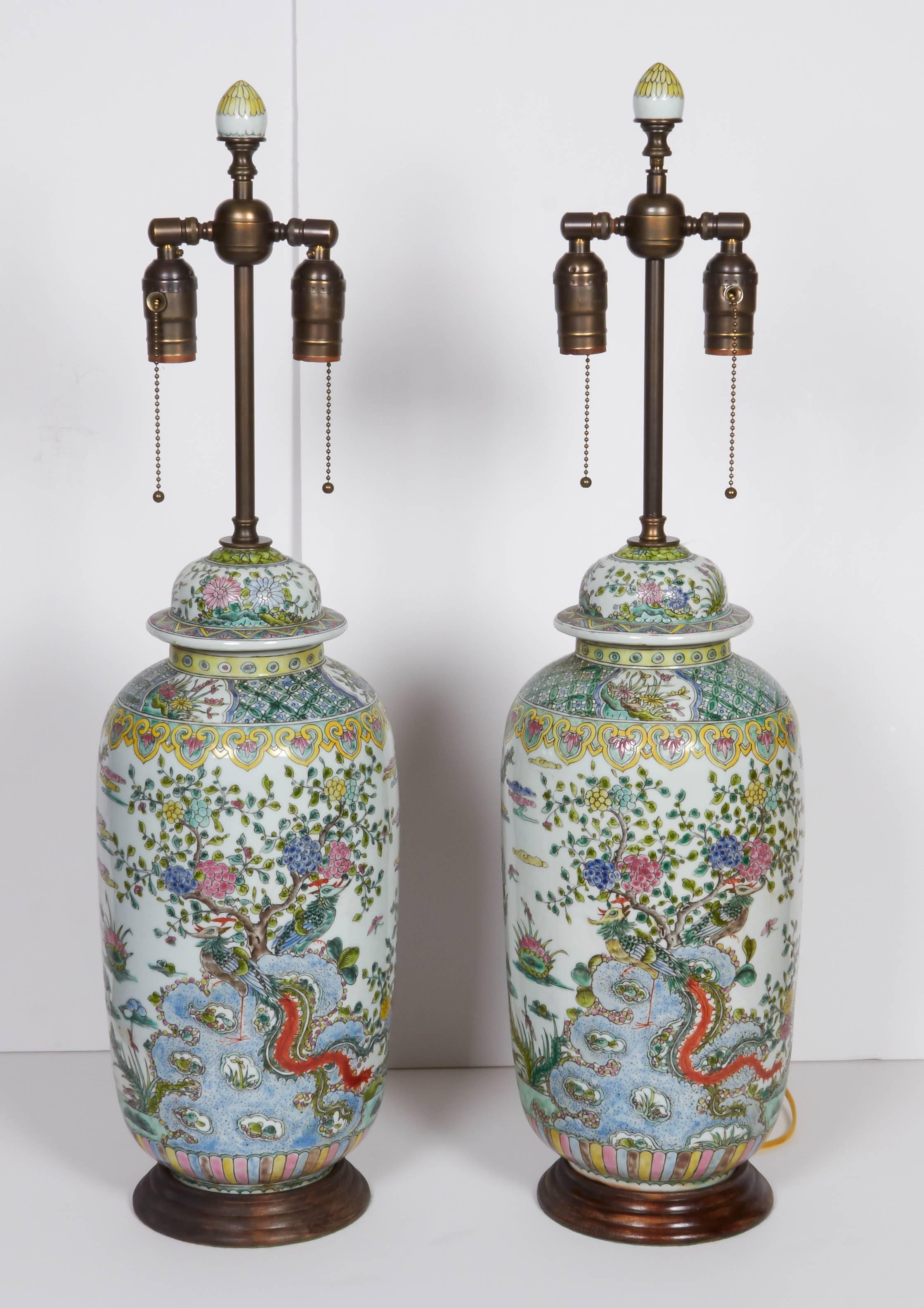 A pair of Chinese porcelain urns fitted as lamps, peacock and floral motif throughout, resting on a wooden base, double cluster socket, wired for electricity
Overall Height- 21.5
Height of urn: 18.5