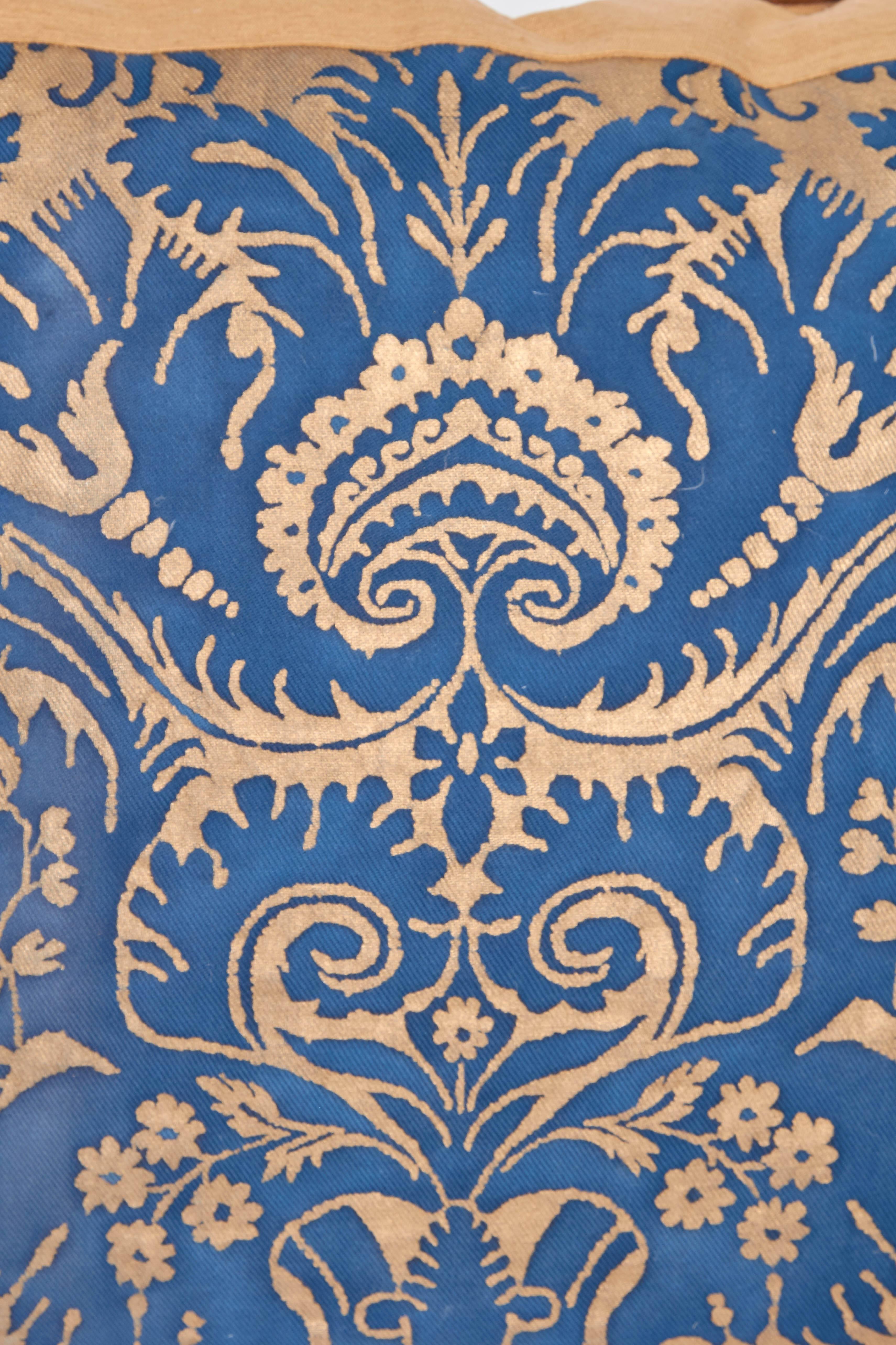 A mitered Fortuny fabric cushion in the DeMedici pattern, the inset fabric in patinated blue on gold ground, silk bias edging and silk blend backing material, the pattern, a 17th century Italian design named for the famous Florentine family, the