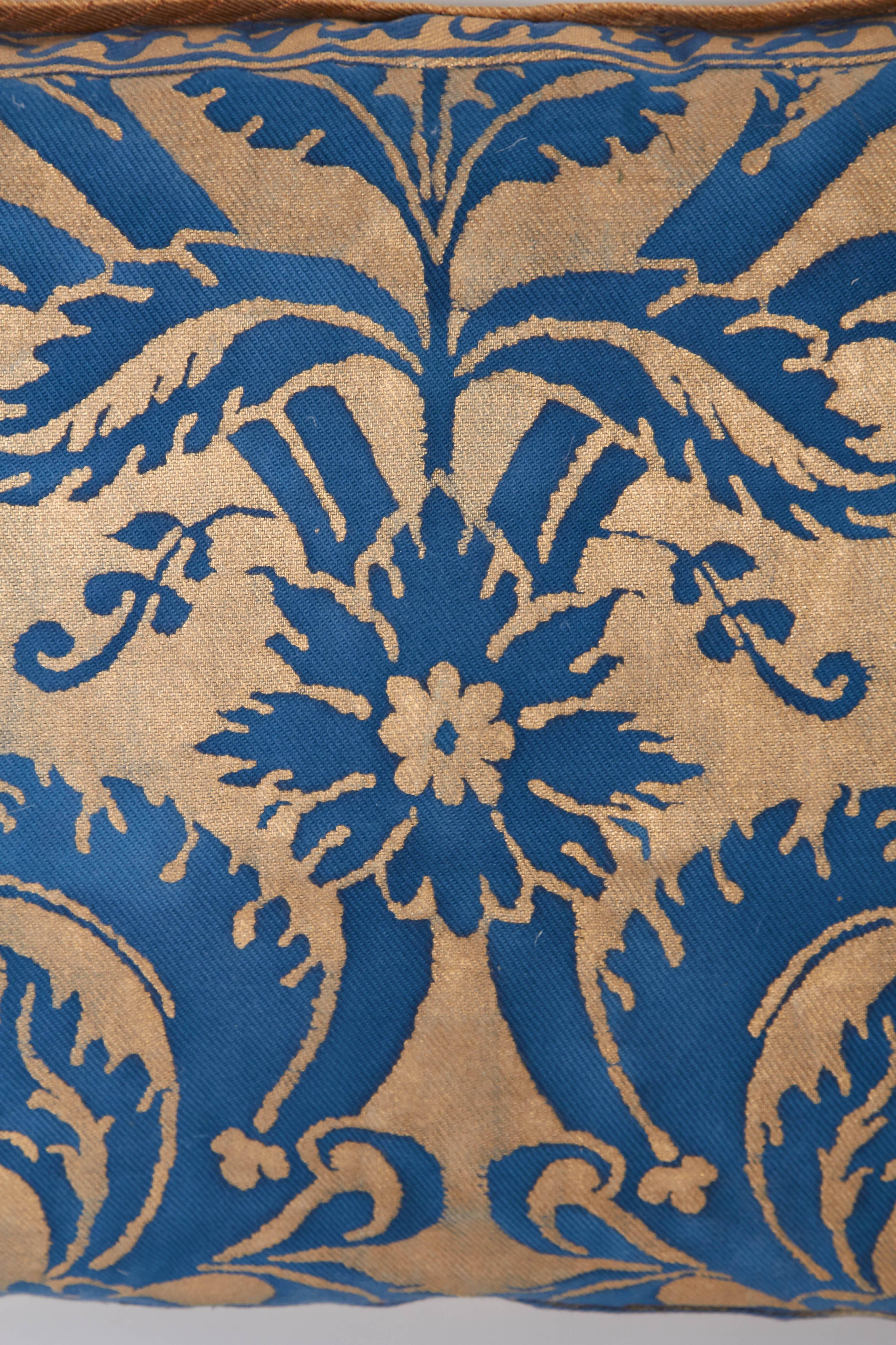 A Fortuny lumbar cushion in the DeMedici pattern, patinated blue on gold ground with stylized Fortuny fabric border, silk blend backing material with silk bias edging, the pattern, a 17th century Italian design named for the famous Florentine