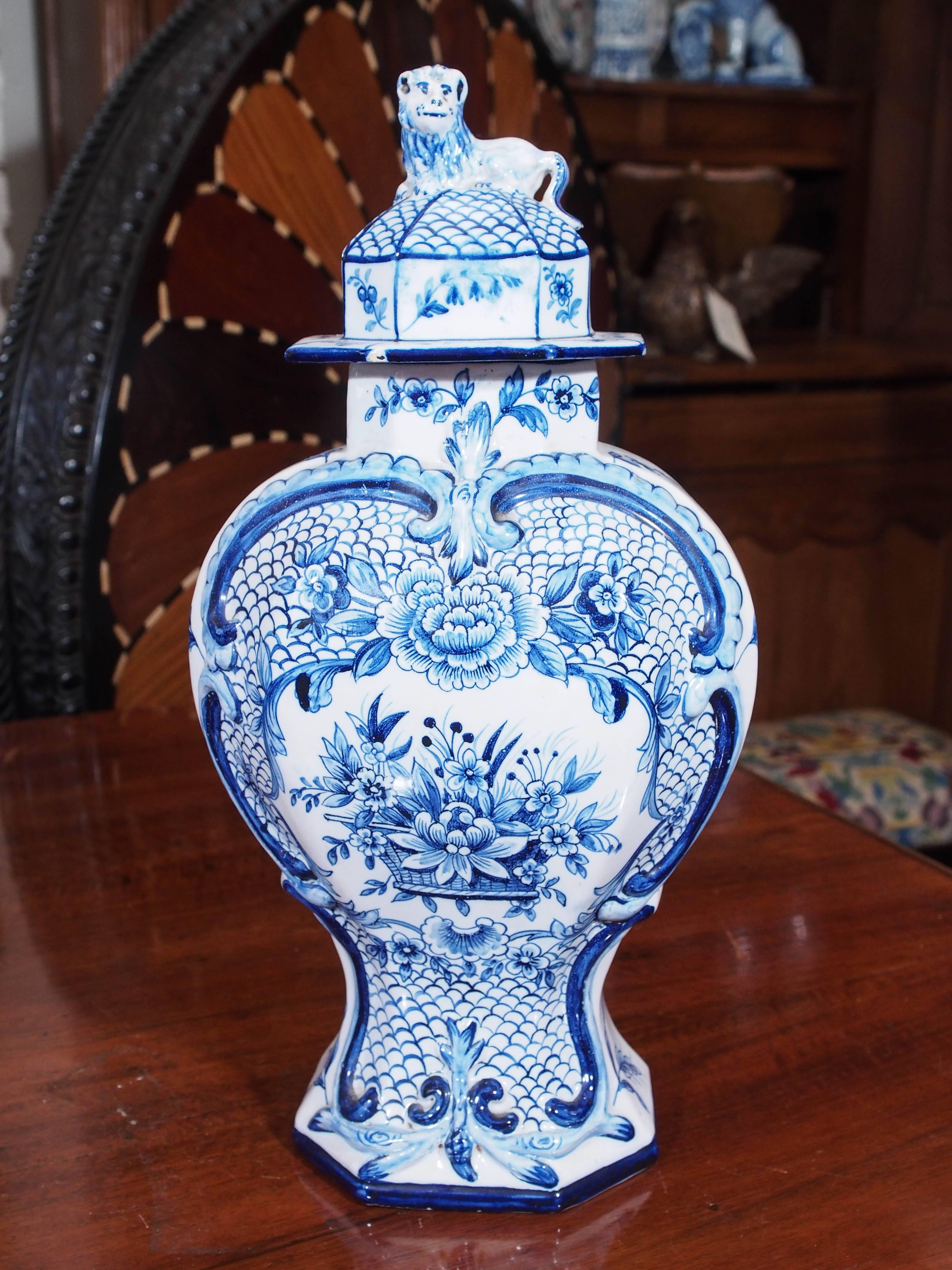 Pair of delft blue and white lidded garniture vases with lion passant finials and floral motif on breast.