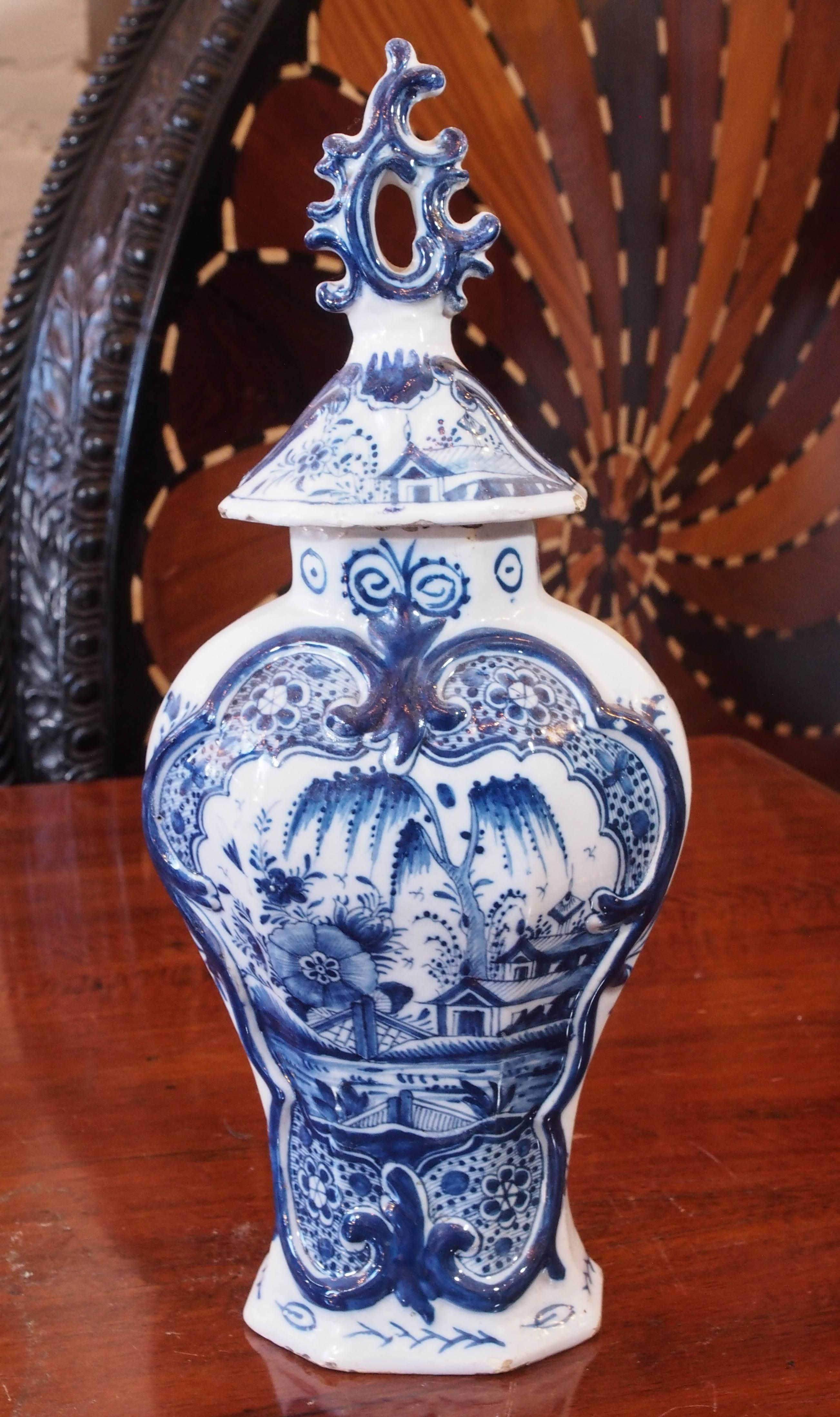 Pair of delft blue and white lidded garniture vases with Baroque finials and chinoiserie scenes.