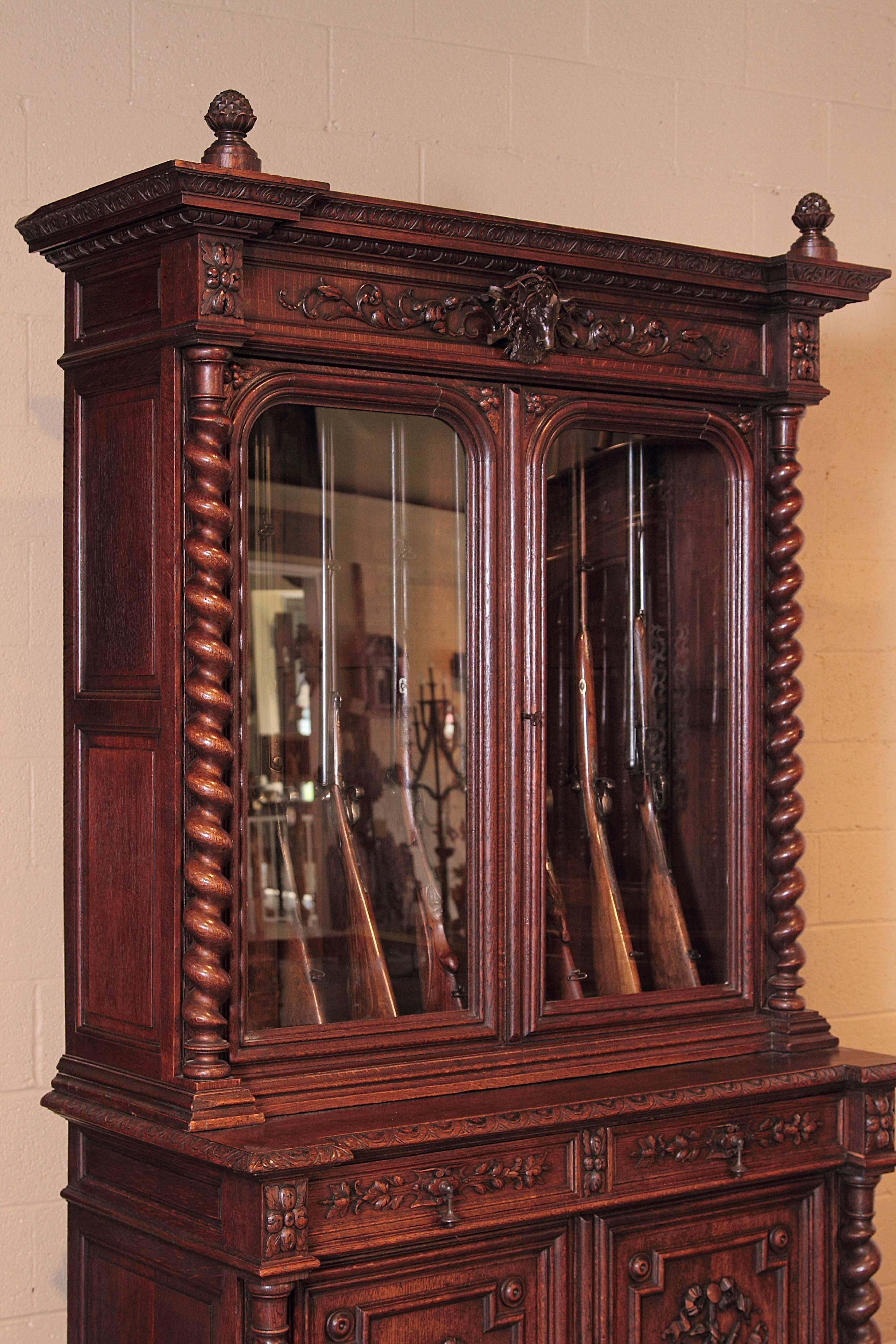 Store your rifle collection inside this beautifully carved, antique gun display cabinet. Created in France, circa 1870, the two-piece buffet for eight guns, features a pair of glass doors across the front, flanked by barley twist columns on both