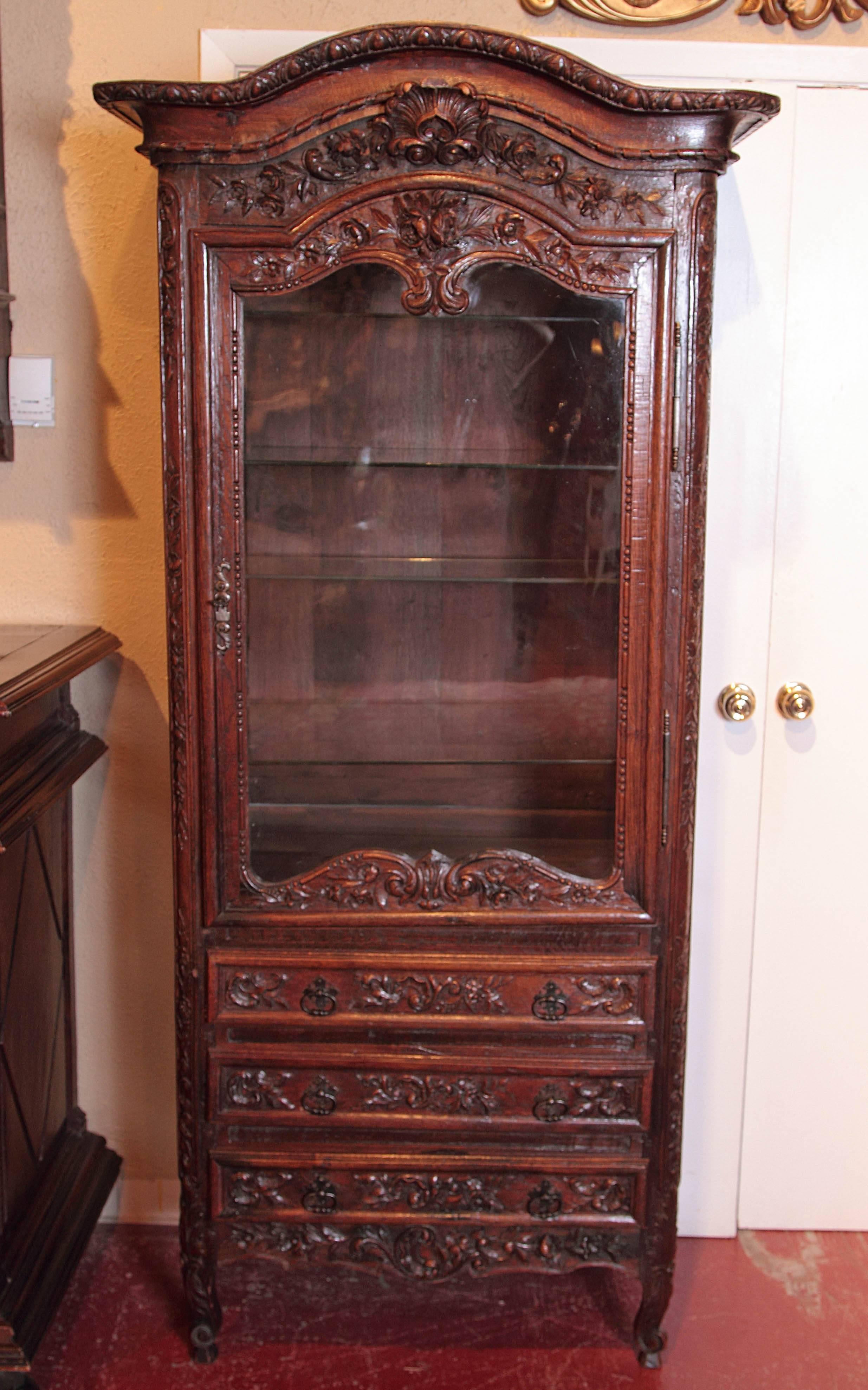Display a treasured collection inside this beautifully hand-carved antique display cabinet from Normandy, France. Crafted circa 1790, the vitrine with bonnet top sits on small scrolled feet and features a glass door across the front revealing four