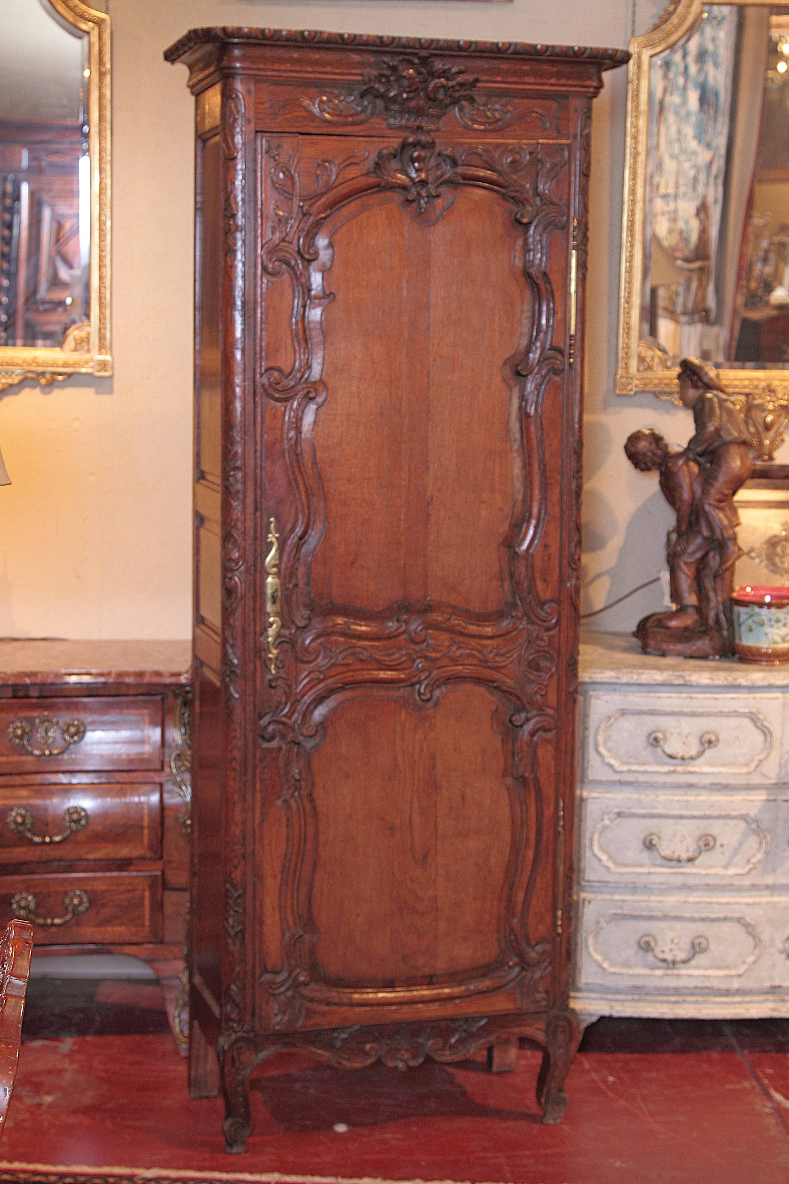 Add beautiful storage to your home with this nicely carved, antique bonnetiere from the Normandy region of France, circa 1820. This one door armoire with four inside shelves features Fine carvings with a detailed flower bouquet, scrolled feet and a