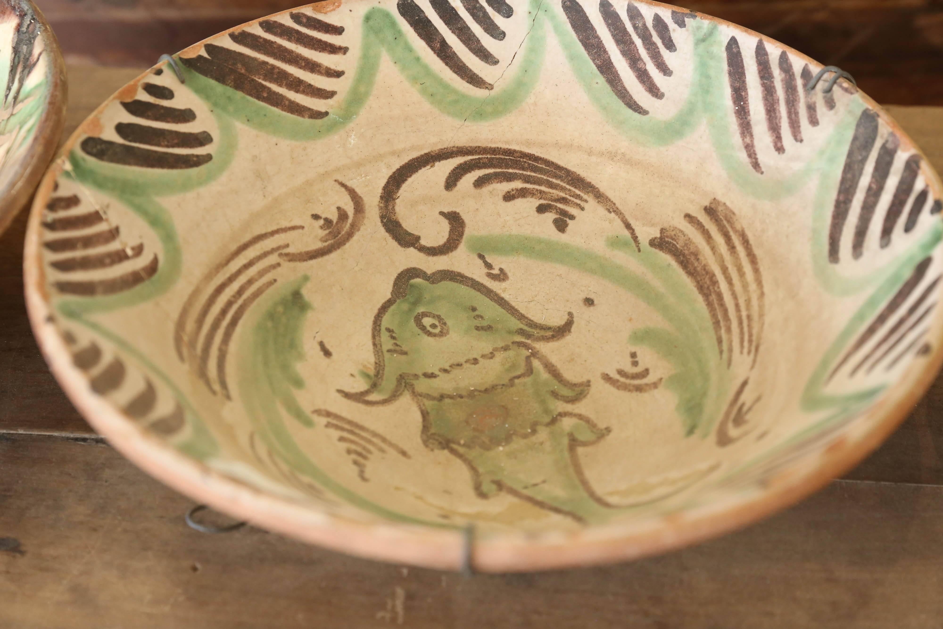 This glazed Valencia Spanish bowl is a great addition to any collector of Spanish artifacts. It's from the late 1800s-early 1900s.  It has green and brown fired paint with a fish motif in the centre.  (Originally the photos shows three bowls.  I
