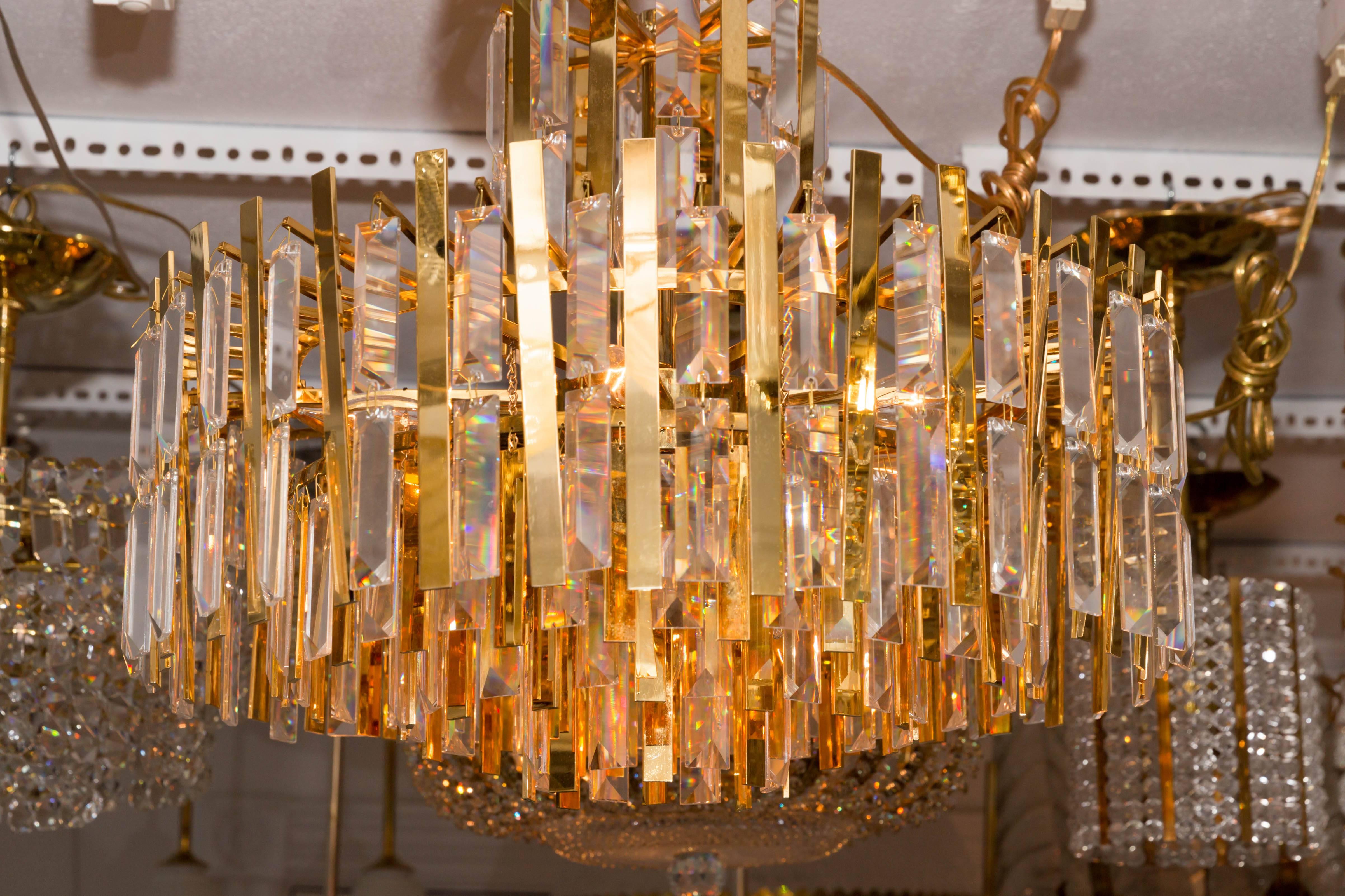 Brass chandelier composed of multiple suspended brass strips and Cyrstal Prisms.