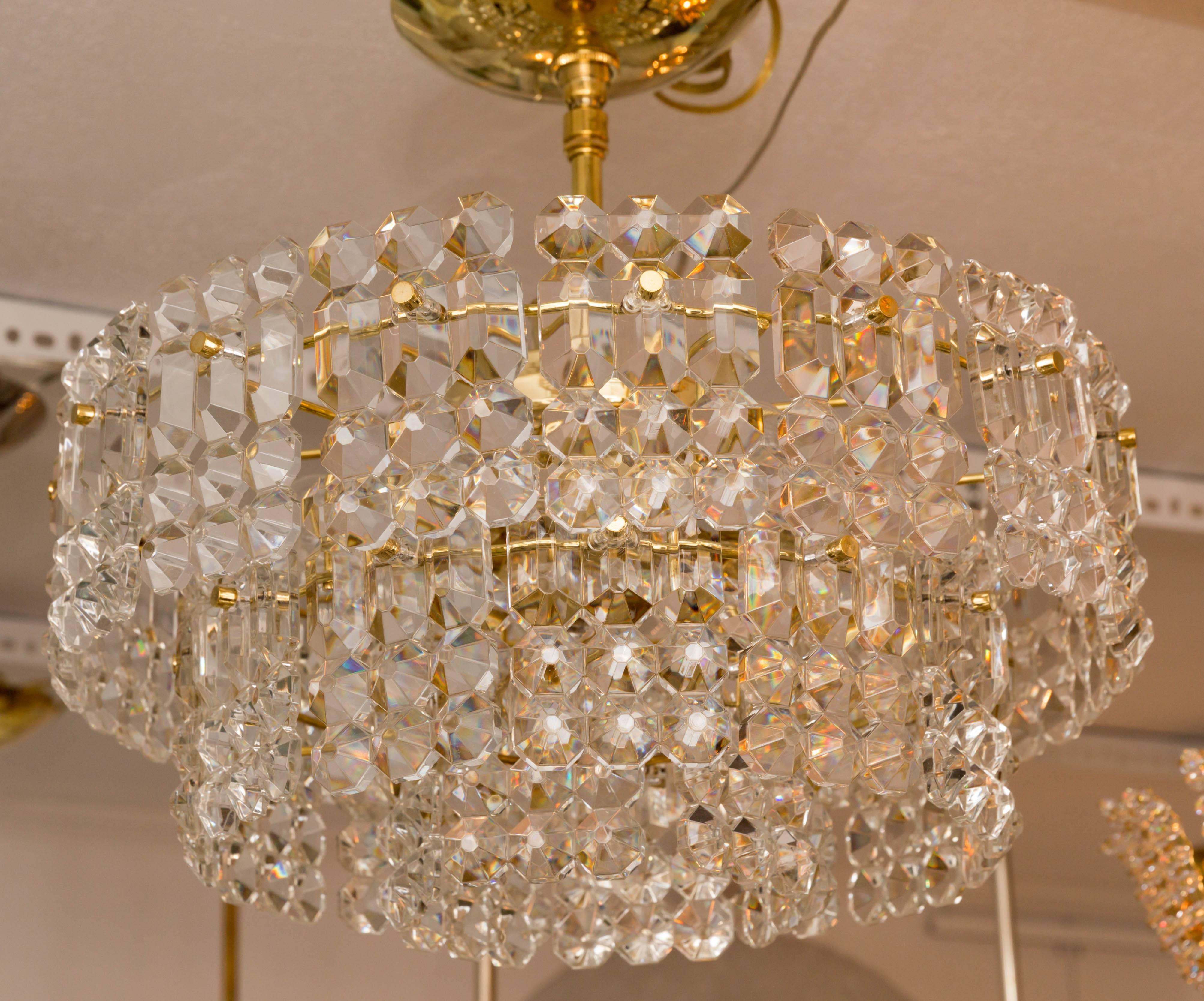 Two-tiered ceiling fixture composed of faceted glass panels with brass detail.