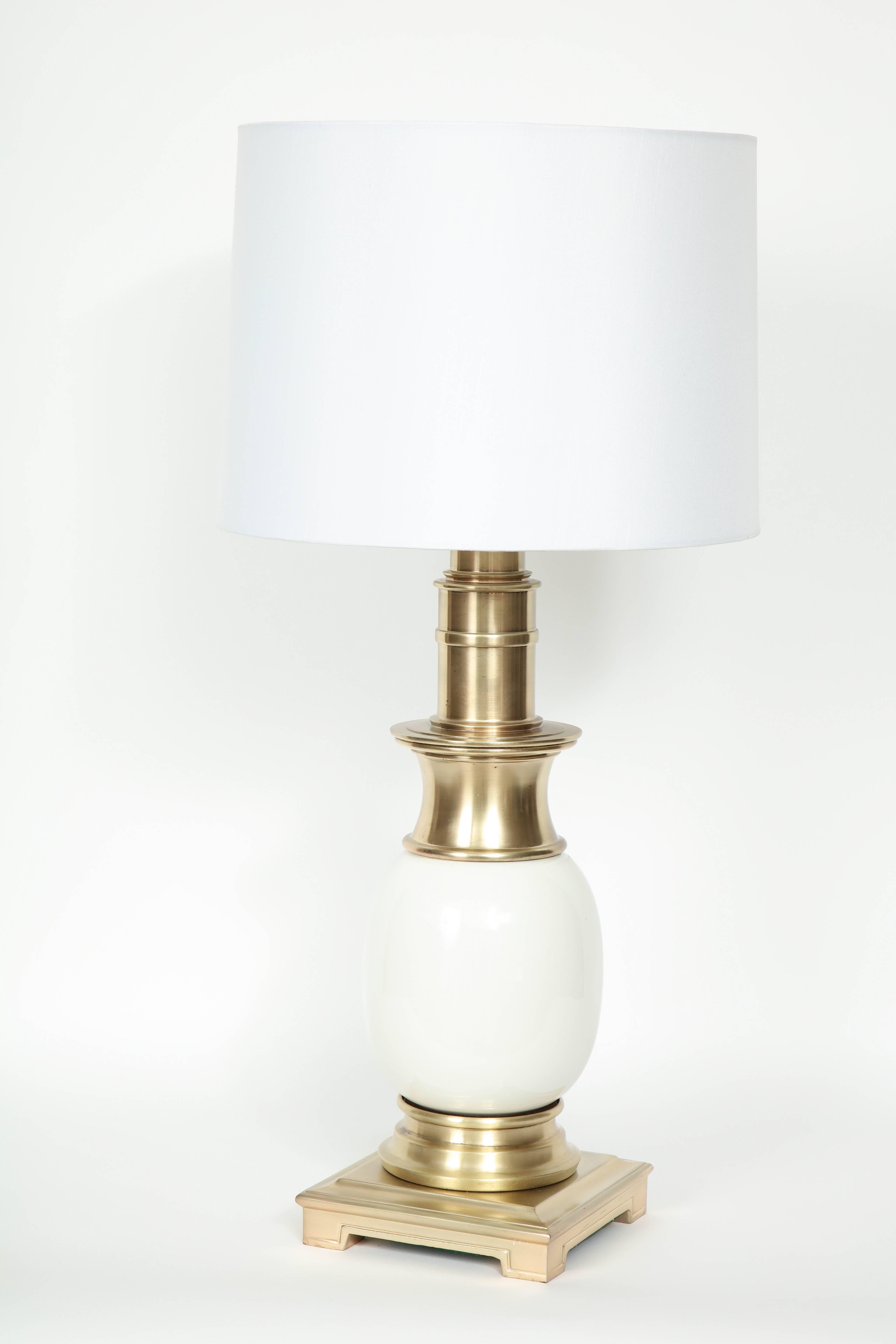 Pair of Mid-Century classically styled lamps featuring satin brass bodies with white glazed ceramic modified Ostrich egg shaped centers. Rewired with brass sockets and new cords. 100W max, shades not included.