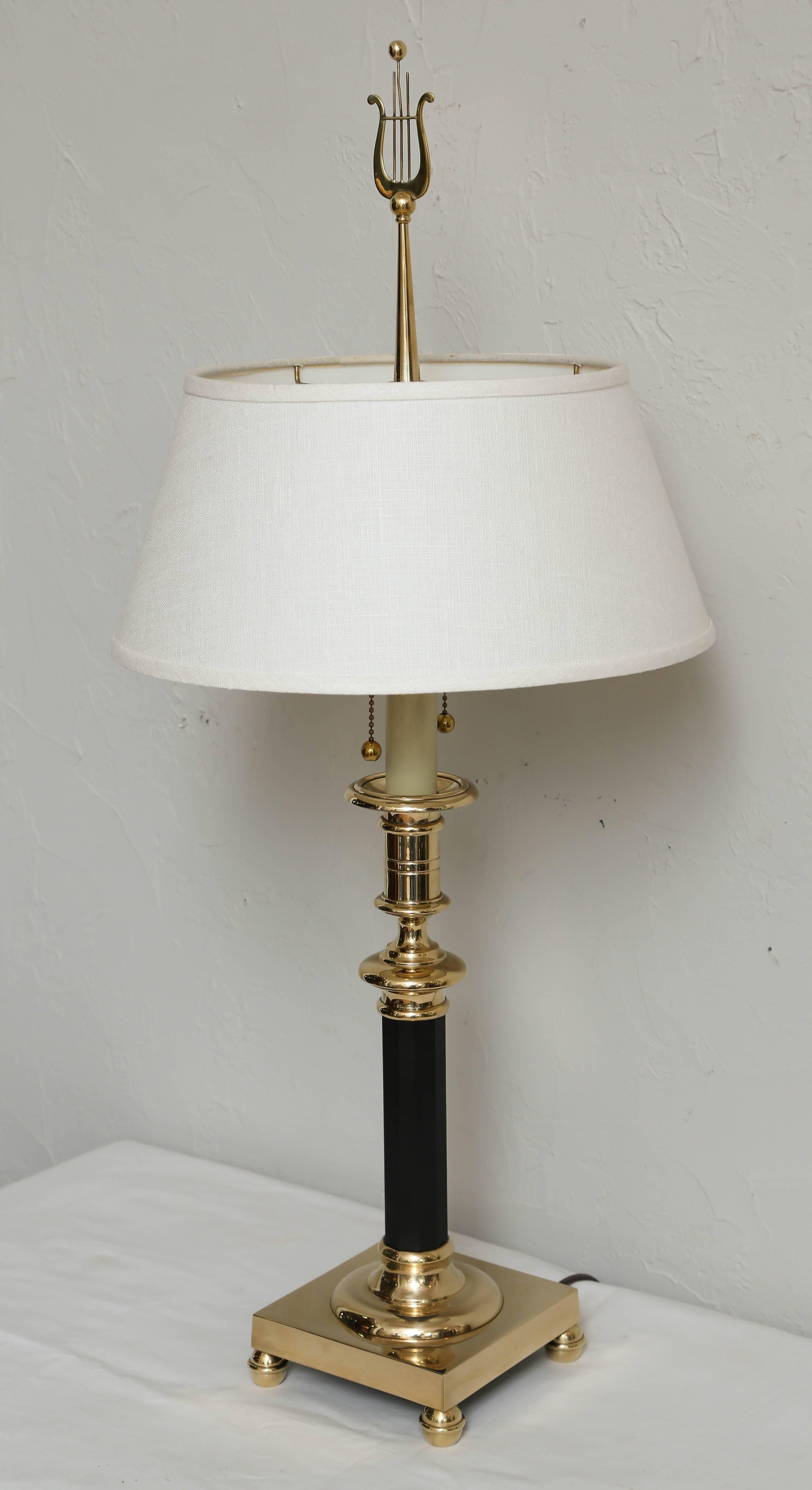 Striking brass candlestick lamp with lyre finial.