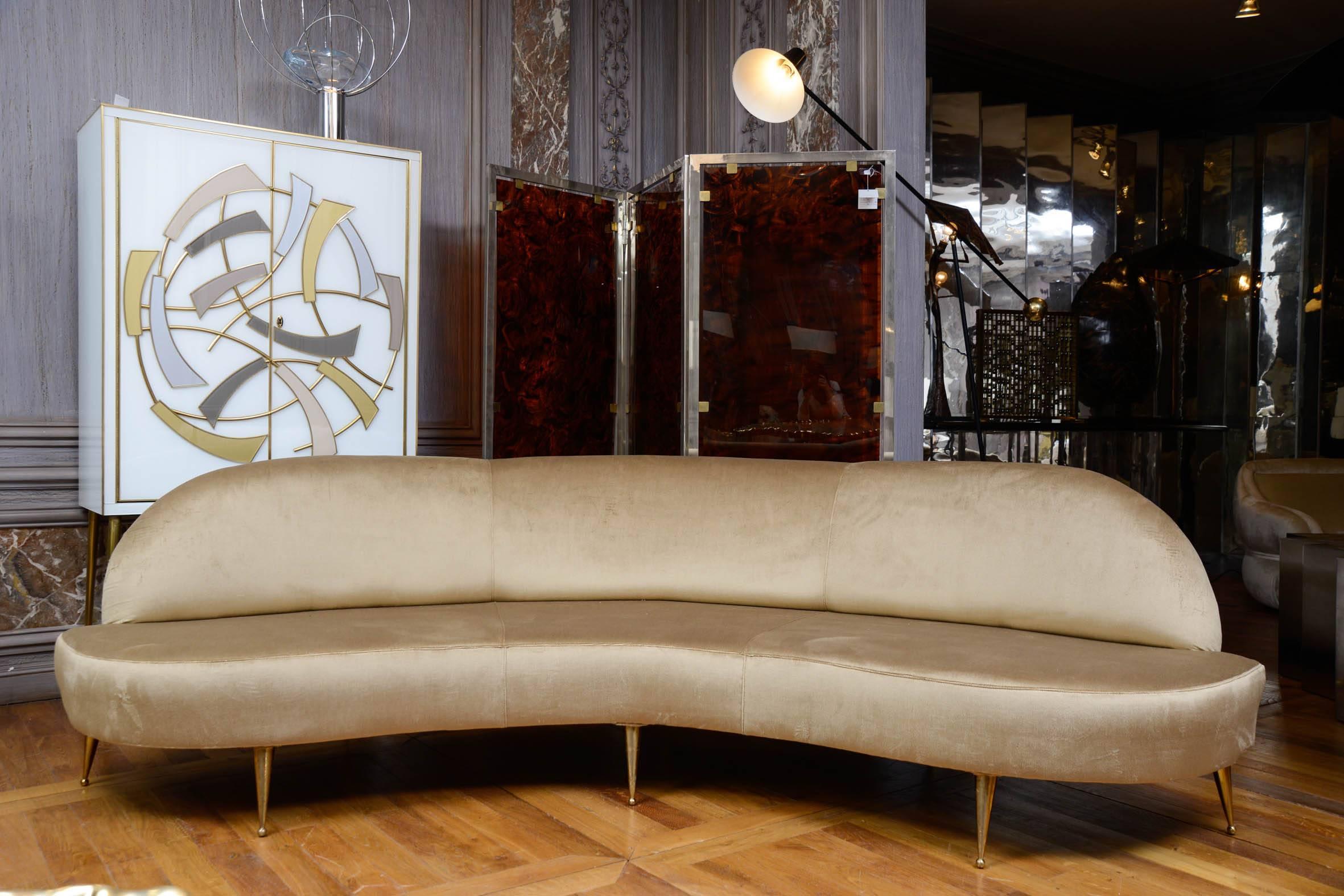 Vintage sofa, serpentine shape, upholstered with beige velvet, eight brass feet.
