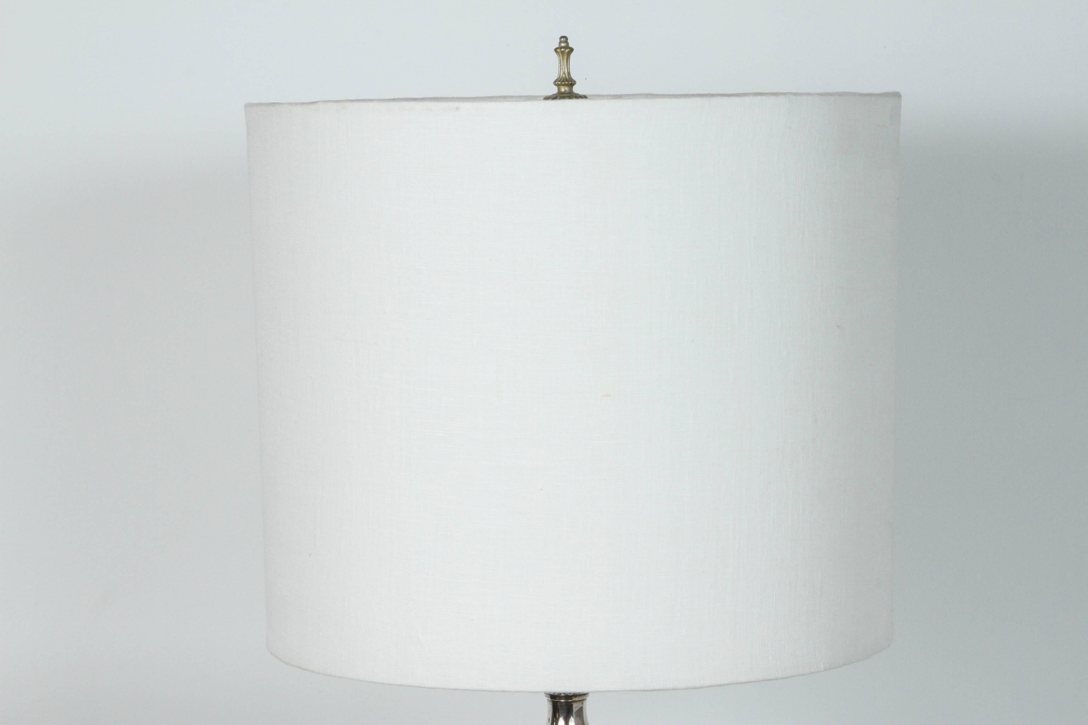American neoclassical table lamp with silvered column and brass base with white linen drum shade.
 
