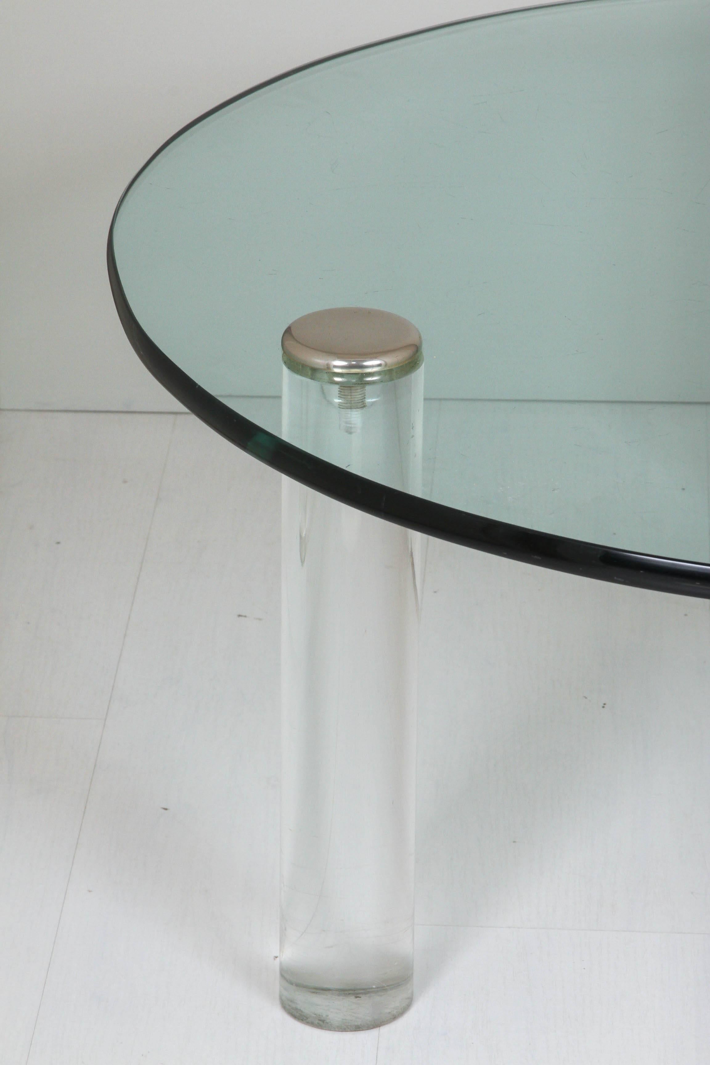3/4" thick laminated clear glass top coffee table supported on three clear Lucite legs caped with metal ends.
 