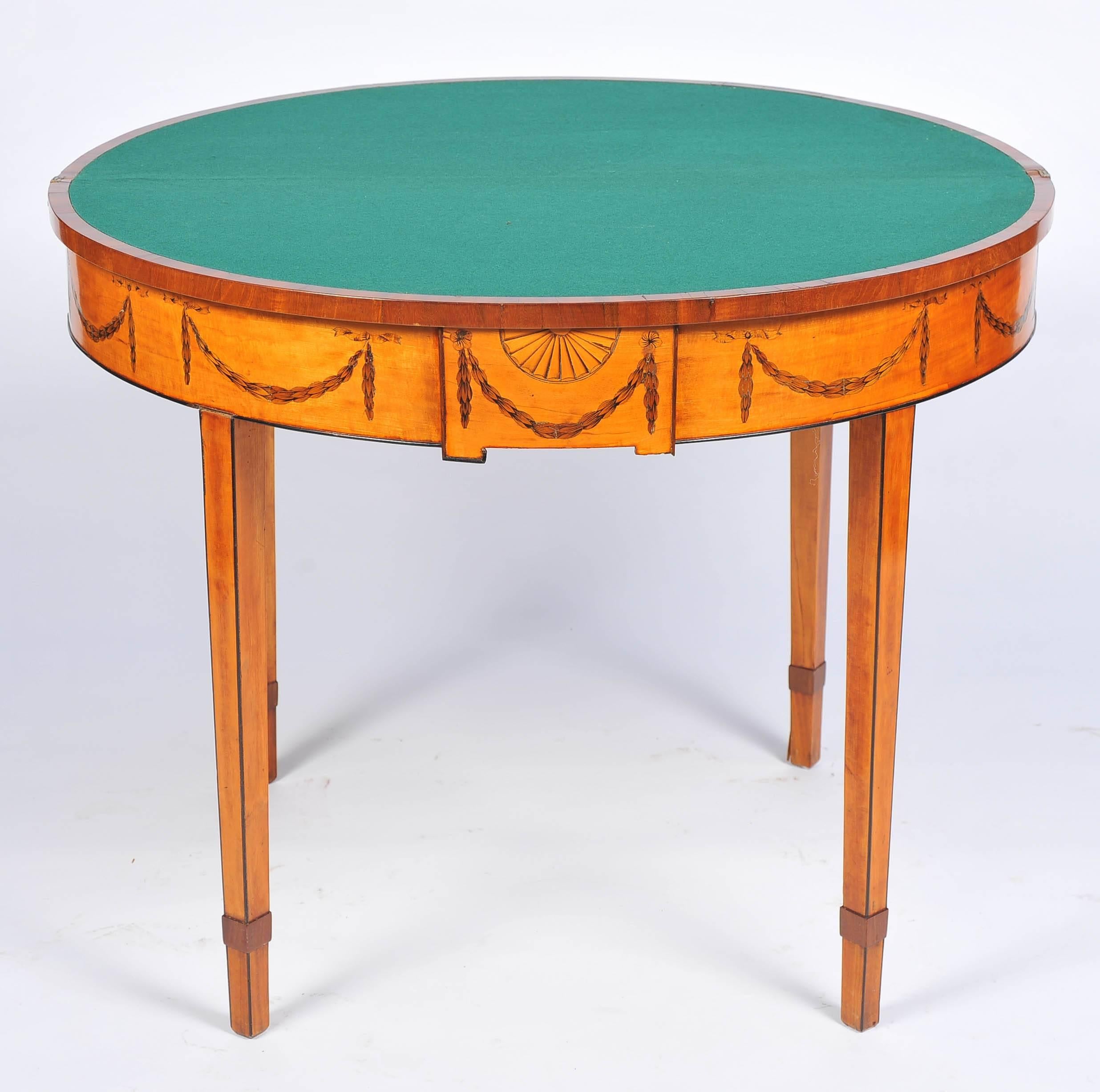 A good quality Sheraton period Satinwood demilune card table, having rosewood crossbanding, a fan inlay to the top, inlaid swags to the frieze and raised on square tapering legs.