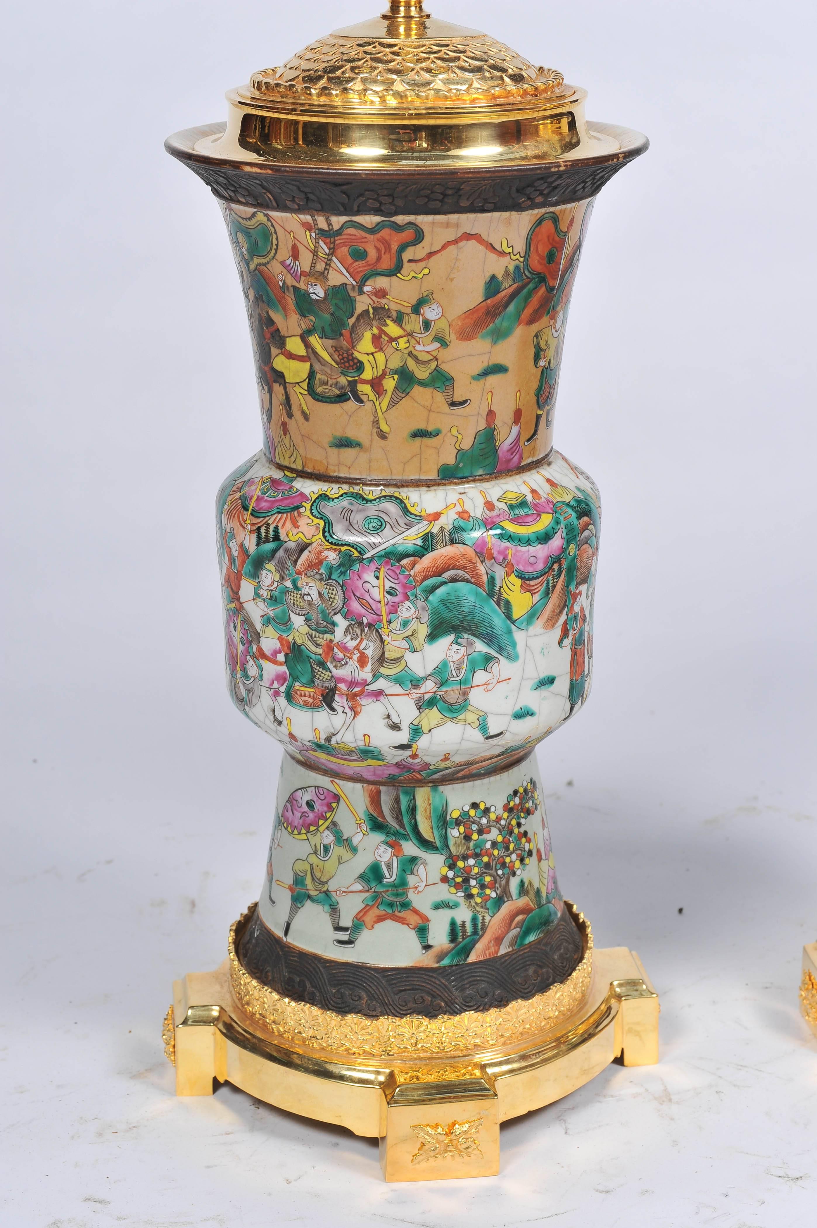 A good quality pair of Chinese 19th century crackleware vases or lamps, each having various classical Chinese scenes of worriers on horse back. Mounted with gilded ormolu bases and tops.