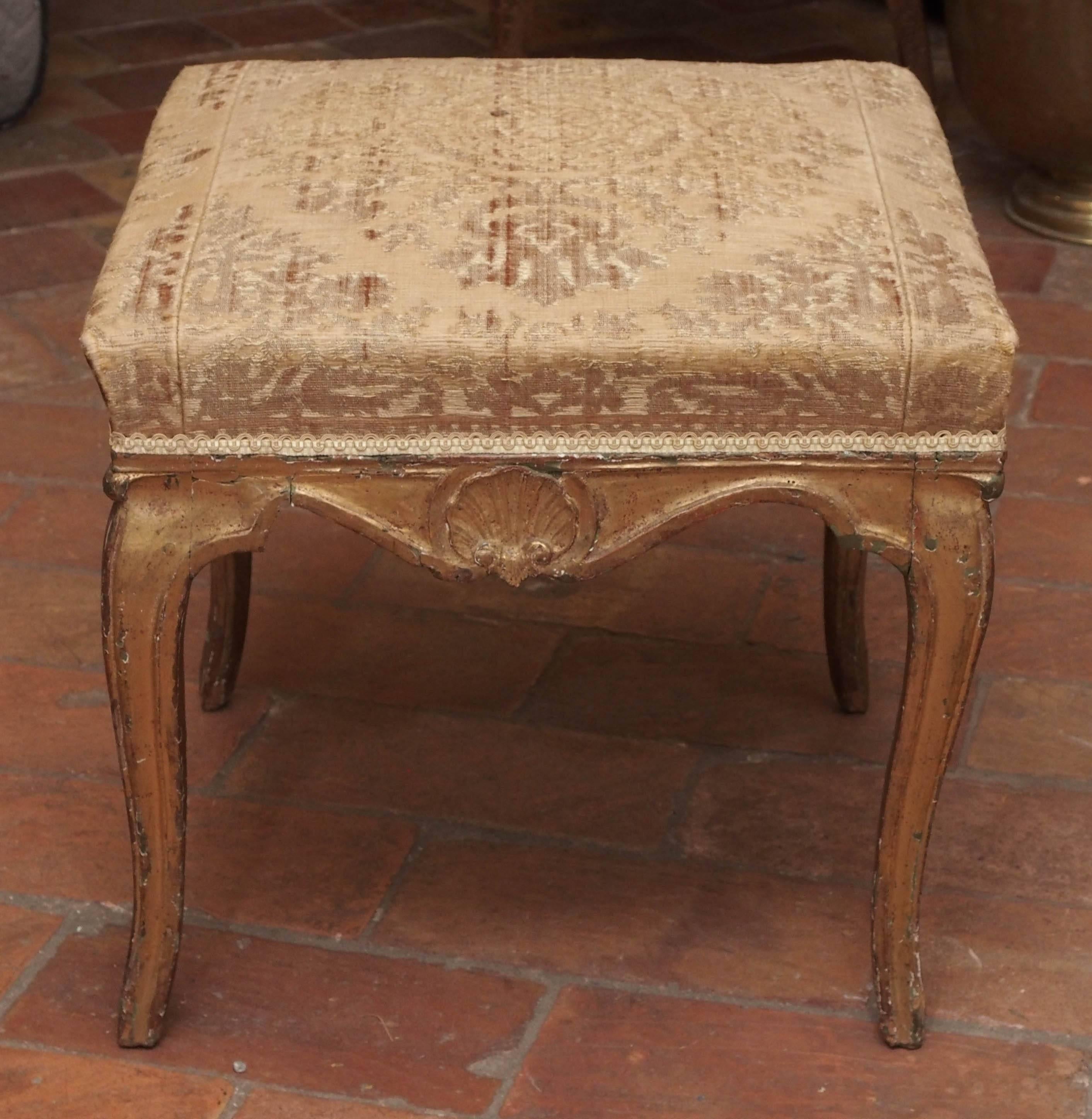 18th century French Louis XIV-Regence hand-carved gilded and upholstered stool from the Fountainbleu area, circa 1720.