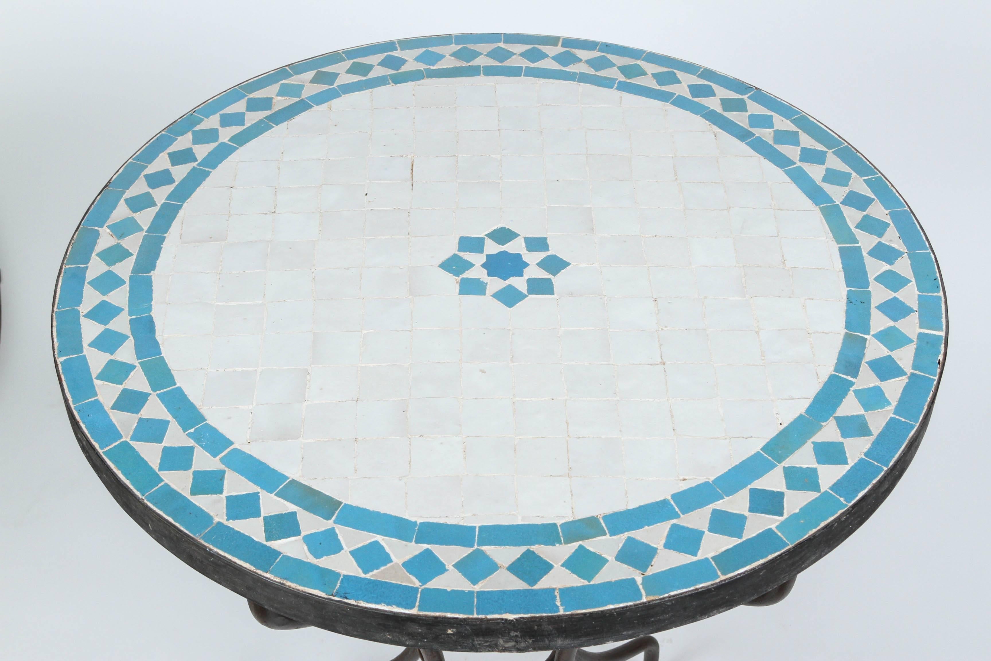Moroccan mosaic tile bistro table on iron base.
Handmade by expert artisans in Fez, Morocco using reclaimed old glazed tiles inlaid in concrete using reclaimed old glazed tiles and making beautiful geometrical designs, colors are turquoise blue and