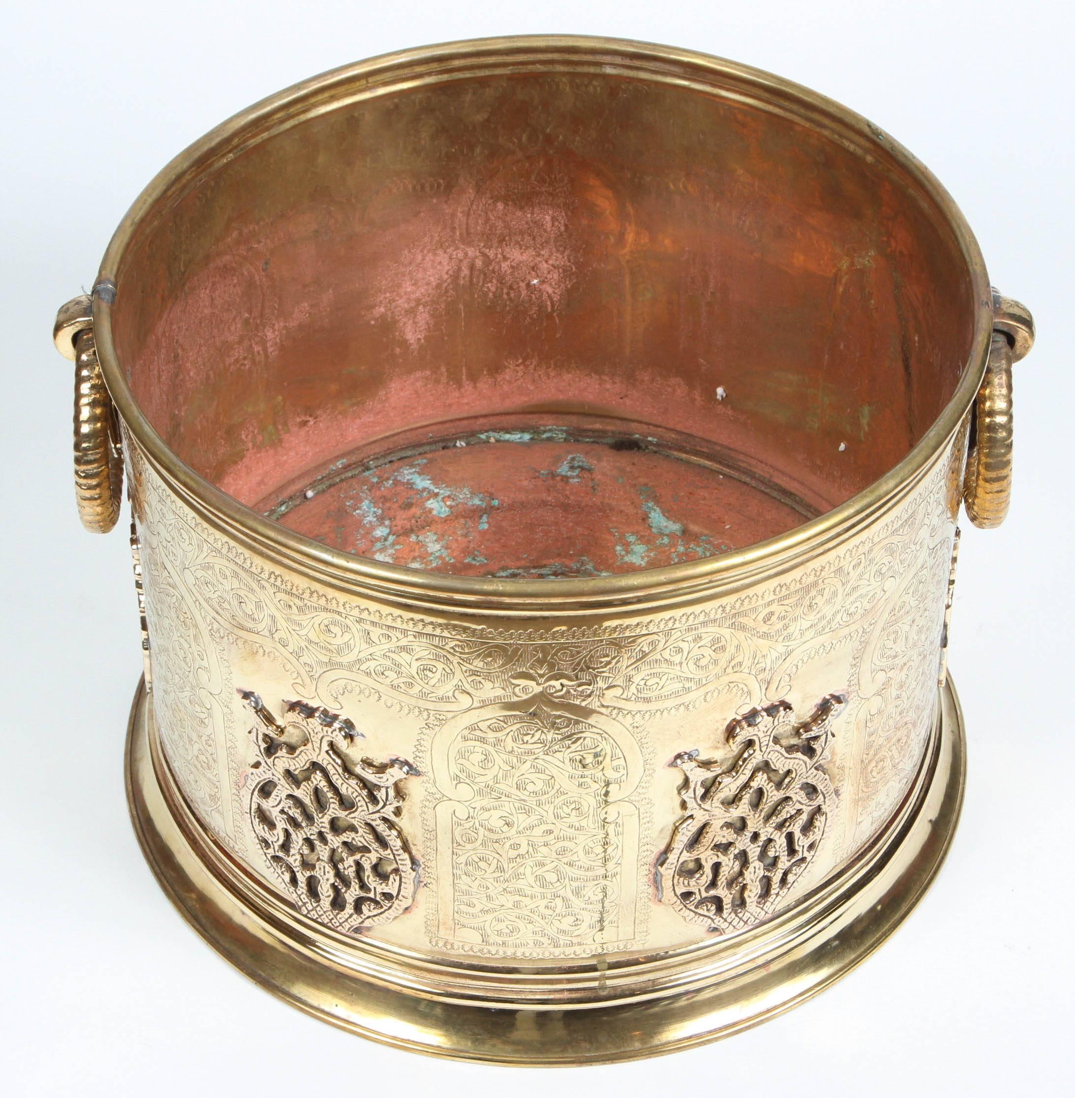 Large Moroccan Moorish polished brass planter, handcrafted and chiselled with fine Moorish arches and foliate designs.
On each side there are a round hand-carved handle, the interior is copper red and polished gold for the exterior.
Very decorative