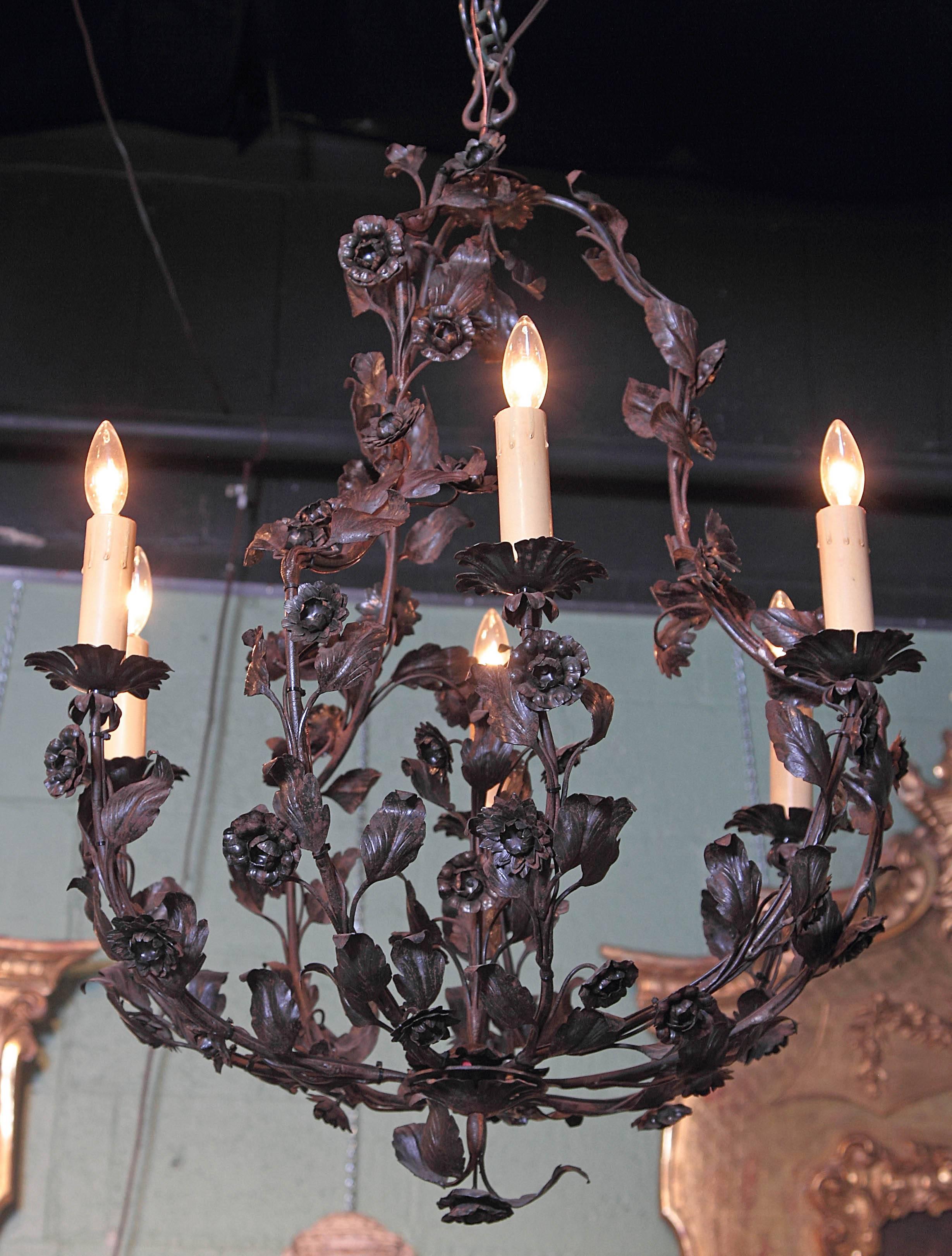 This elegant tole chandelier is rounded in shape and is beautifully embellished with over 100 tole flowers and leaves. Crafted in France, circa 1900, the fixture has a large centre finial and an organic, asymmetrical shape that stands out from the