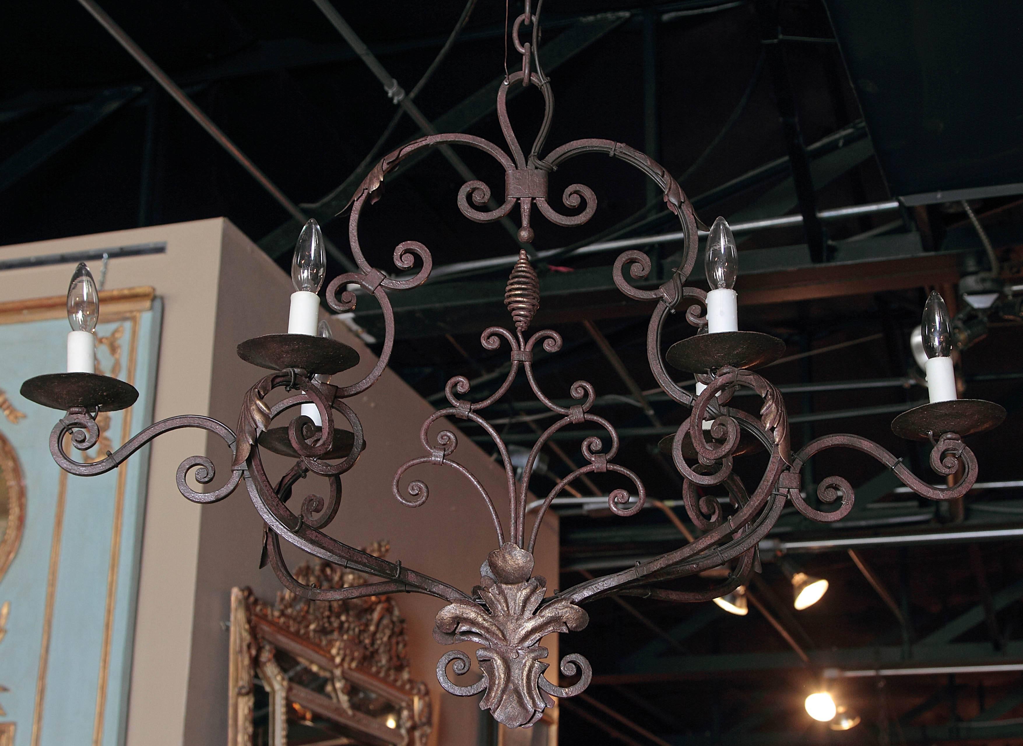 This elegant, scrolling, oblong chandelier would make a lovely addition to a home of any style. Crafted in France circa 1900, the iron light fixture features six scrolled arms newly wired, and curling center finial at the base embellished by back to