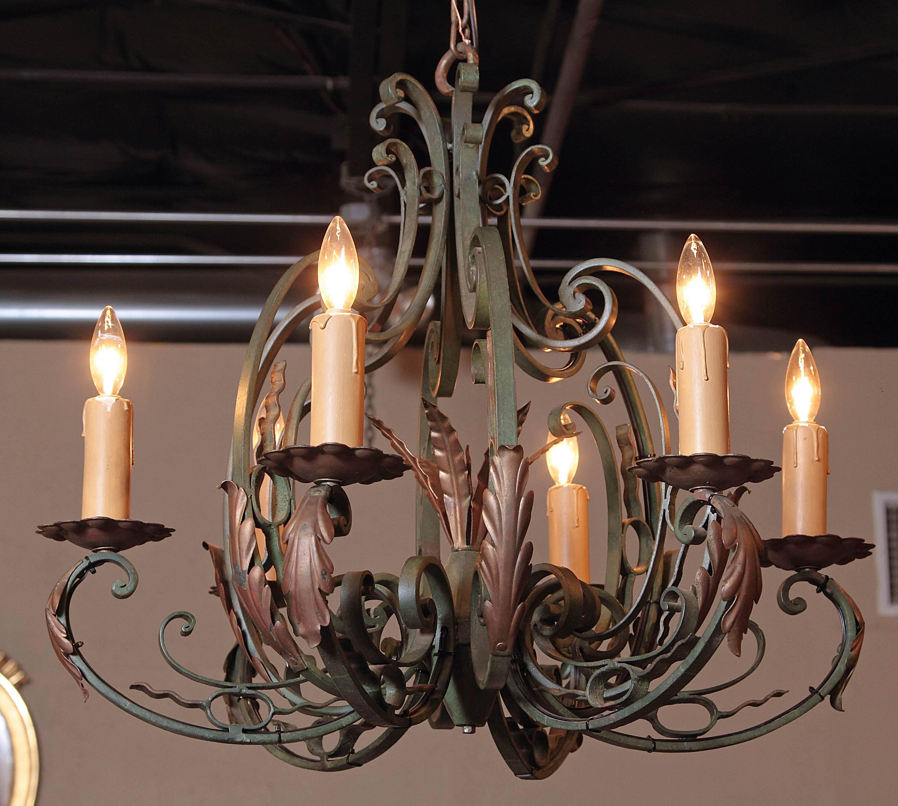 This turn of the century iron chandelier would make a beautiful decorative addition to a bedroom, breakfast room or living room. Crafted in France, circa 1920, the rustic light fixture has a scrolling base and six scrolled arms with their original
