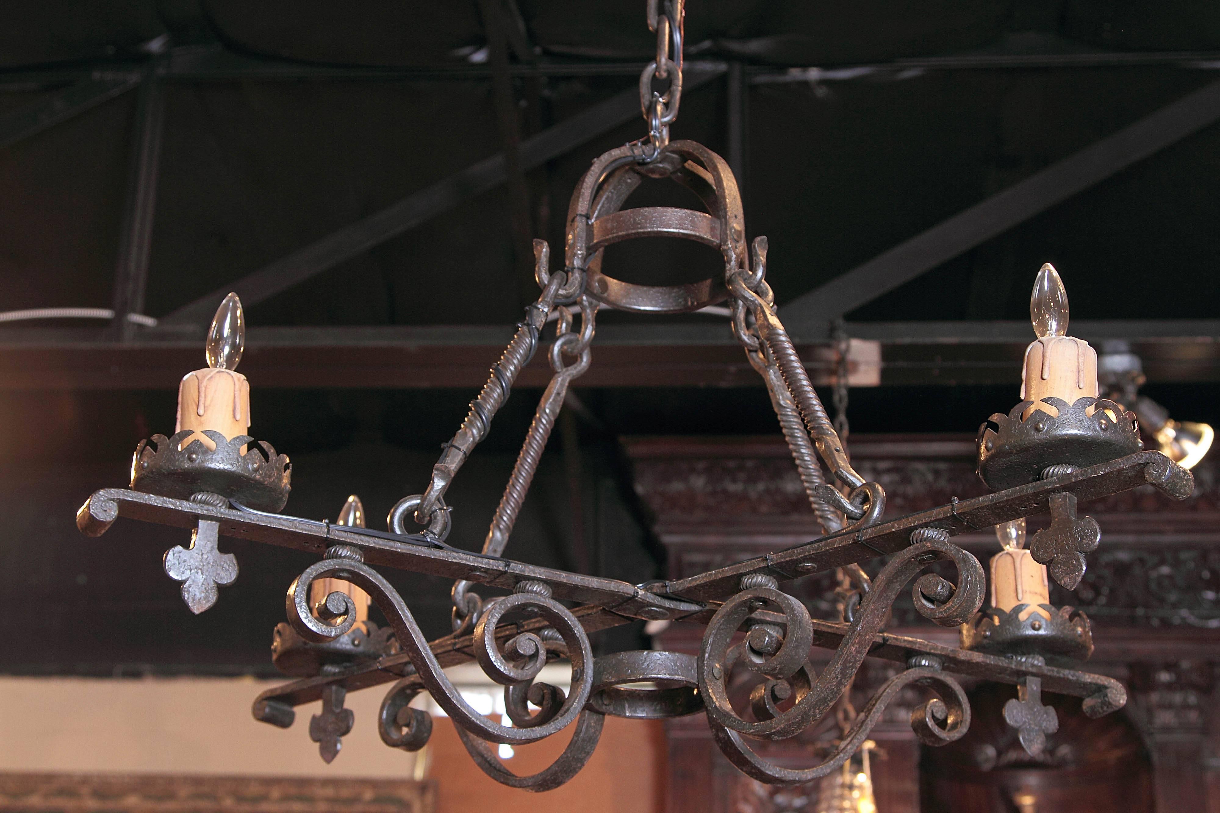 For a rustic, Gothic home, look no further than this heavy iron chandelier. Forged in France, circa 1880, the chandelier has a simple shape and four lights. The weighted fixture has its original wooden candle holders, crown and chain. In terms of