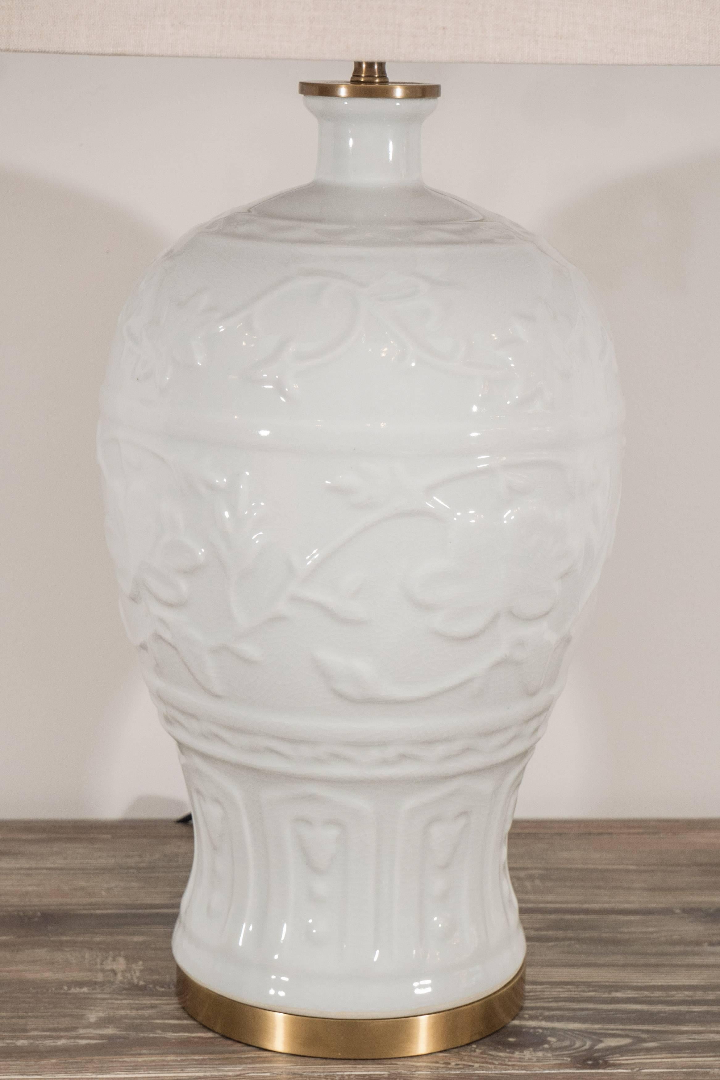 This pair of white ceramic lamps have a lovely crackled finish with a charming floral and left design. The lamps are on a brass base and include natural linen drum shades.