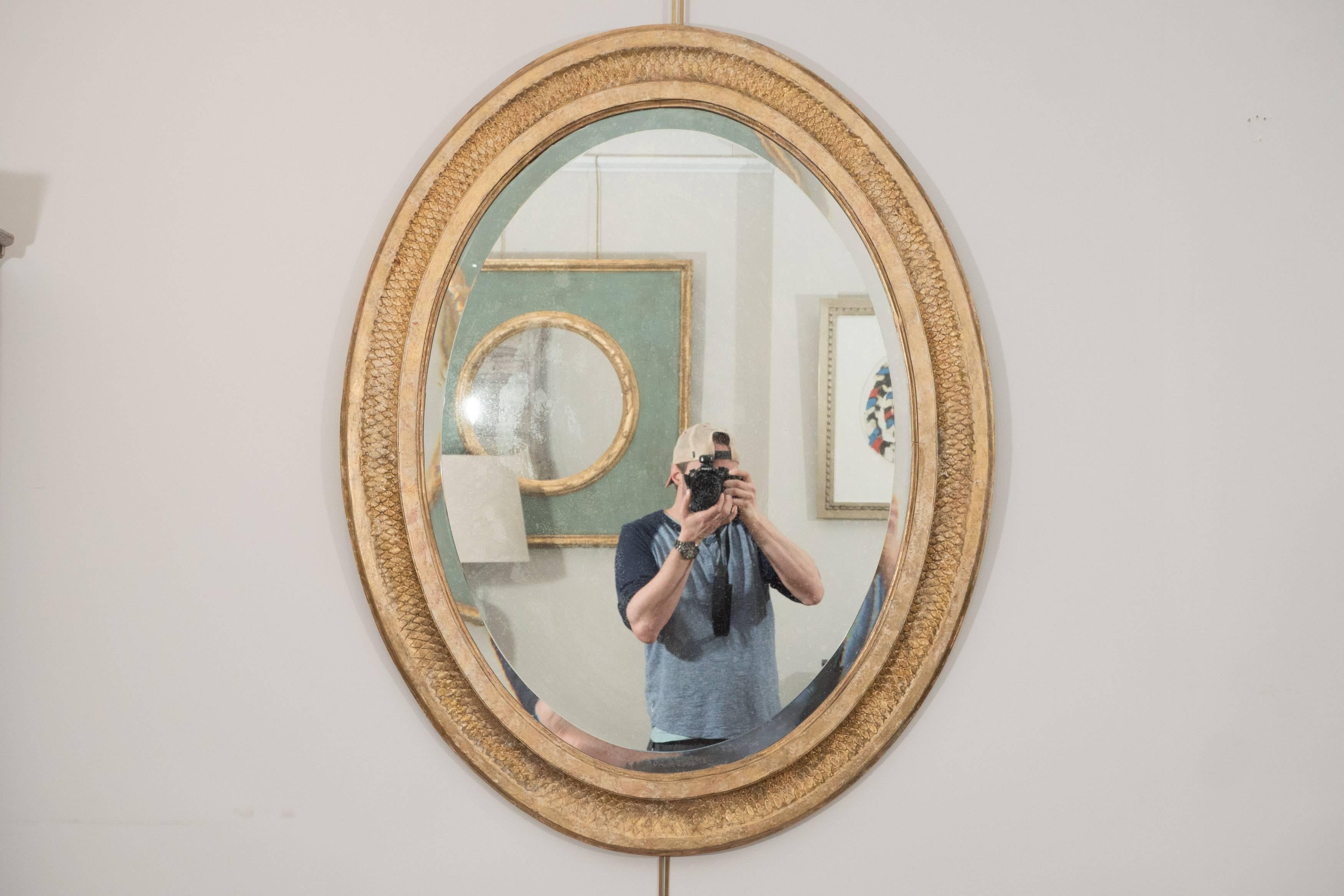 This mirror is a standout in terms of quality and workmanship. The oval beveled glass plate is set within a conforming giltwood frame featuring beautifully carved detail channeled between two molded edges. This gem is refined and elegant and would