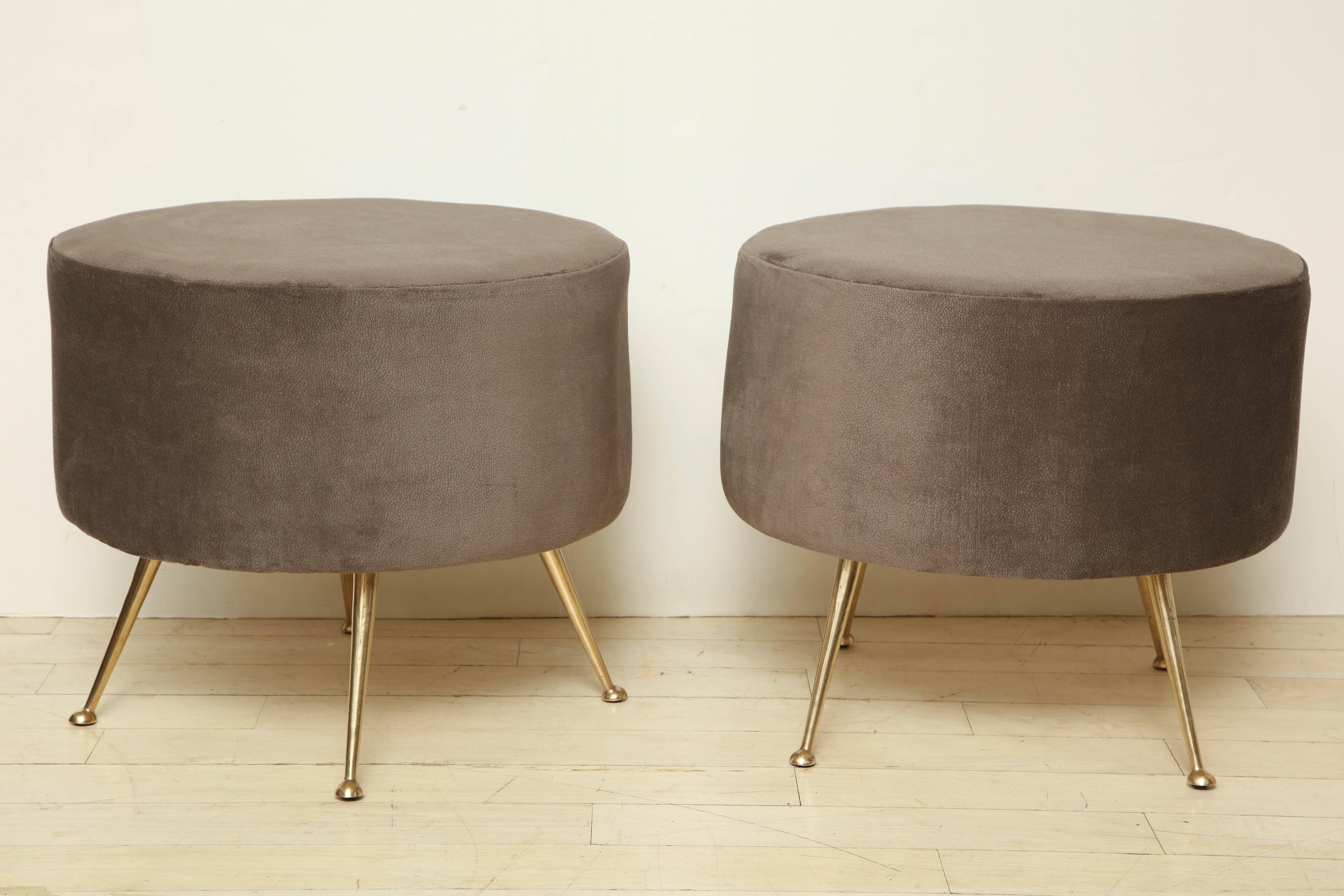 Pair of Mid-Century round poufs upholstered in a grey velveteen on splayed brass legs, Italy, circa 1960.