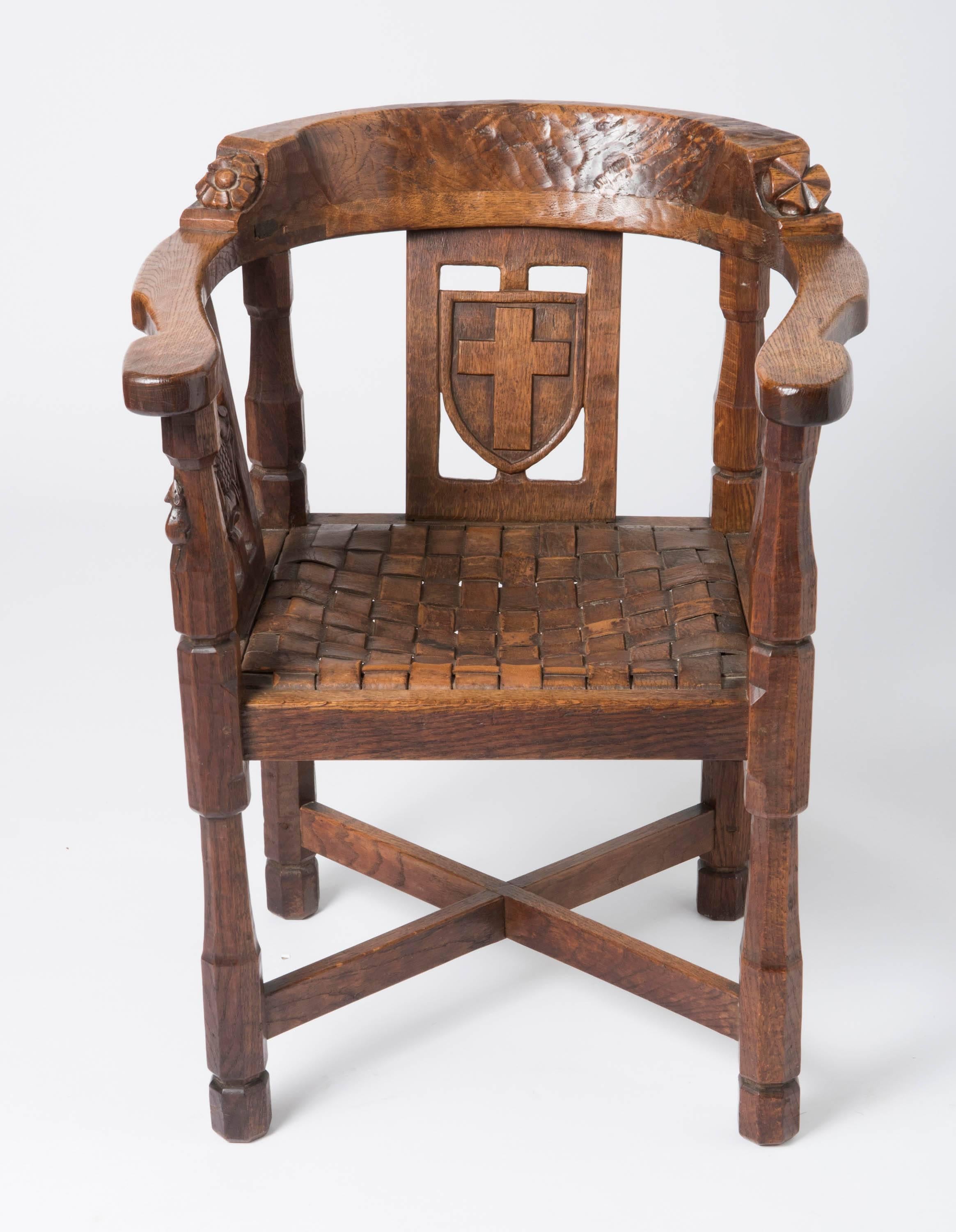 An important and rare early Robert “Mouseman” Thompson Monks chair.
Oak.
The curved back with shaped arms. Each side with a carved flower head and a five cone symbol over three panels. The central panel carved with a cross and a shield. The sides
