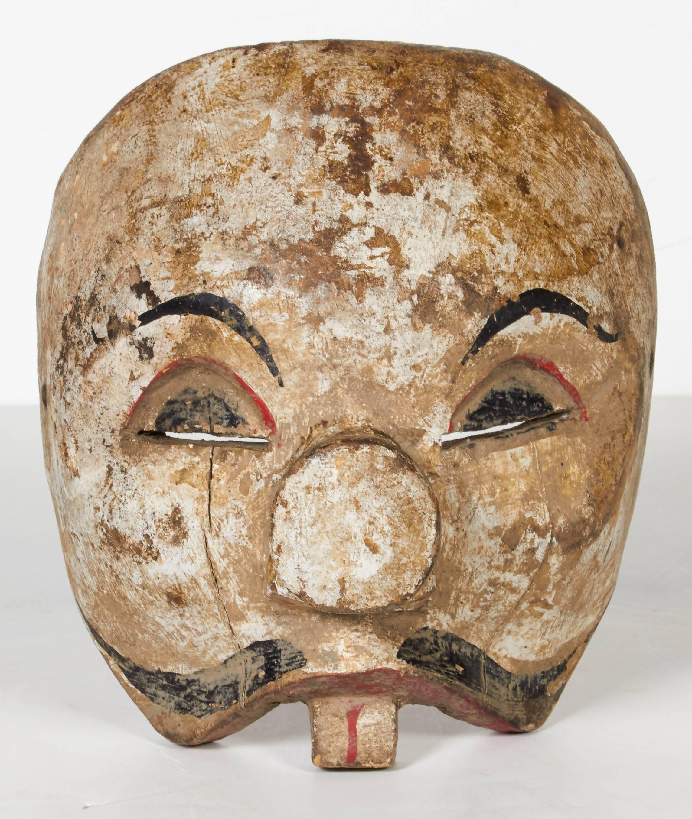 A beautifully patinated early 20th century Balinese clown mask with original paint. This handmade and skilfully carved mask was used in dance ceremonies. This piece can be displayed on a wall or its shape naturally allows it to sit straight up on a