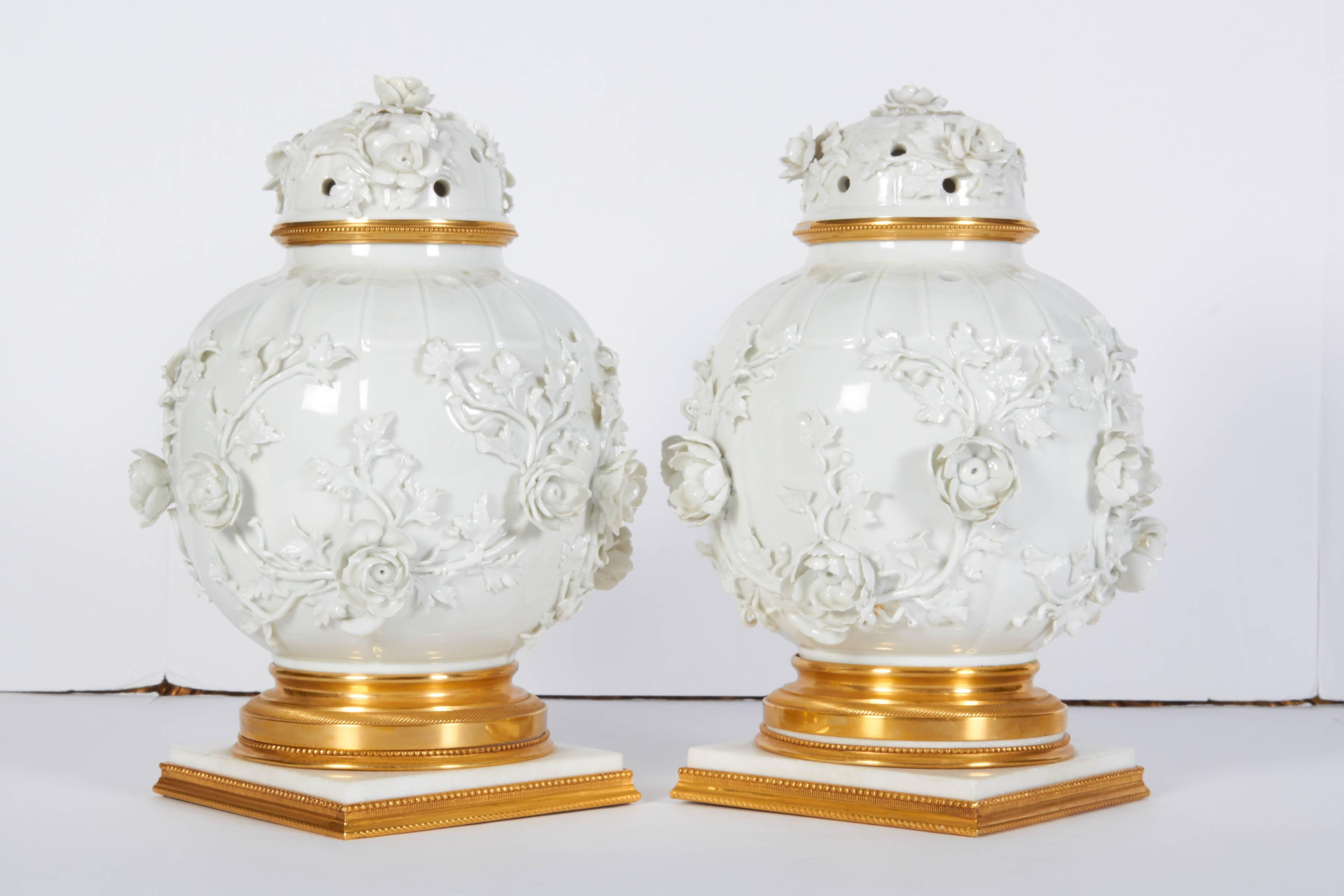 Une belle paire de vases et de couvercles de Potpouri en porcelaine blanche de Chine et en bronze doré de style Louis XVI, avec des fleurs et des feuilles appliquées en relief. Les vases en porcelaine de Chine ancienne montés dans des montures en